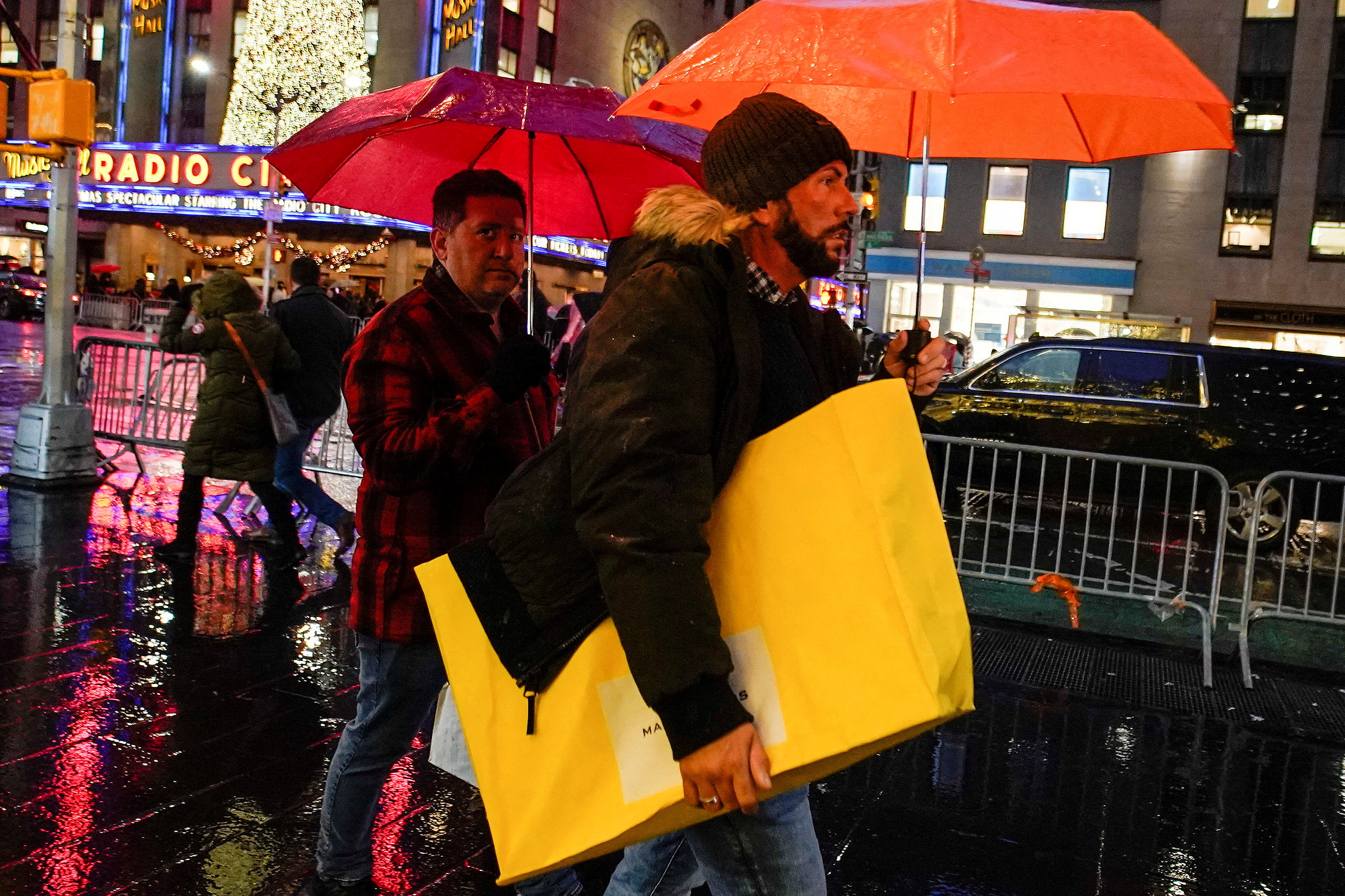 A man walks under the rain with his shopping bag during the holiday season in New York