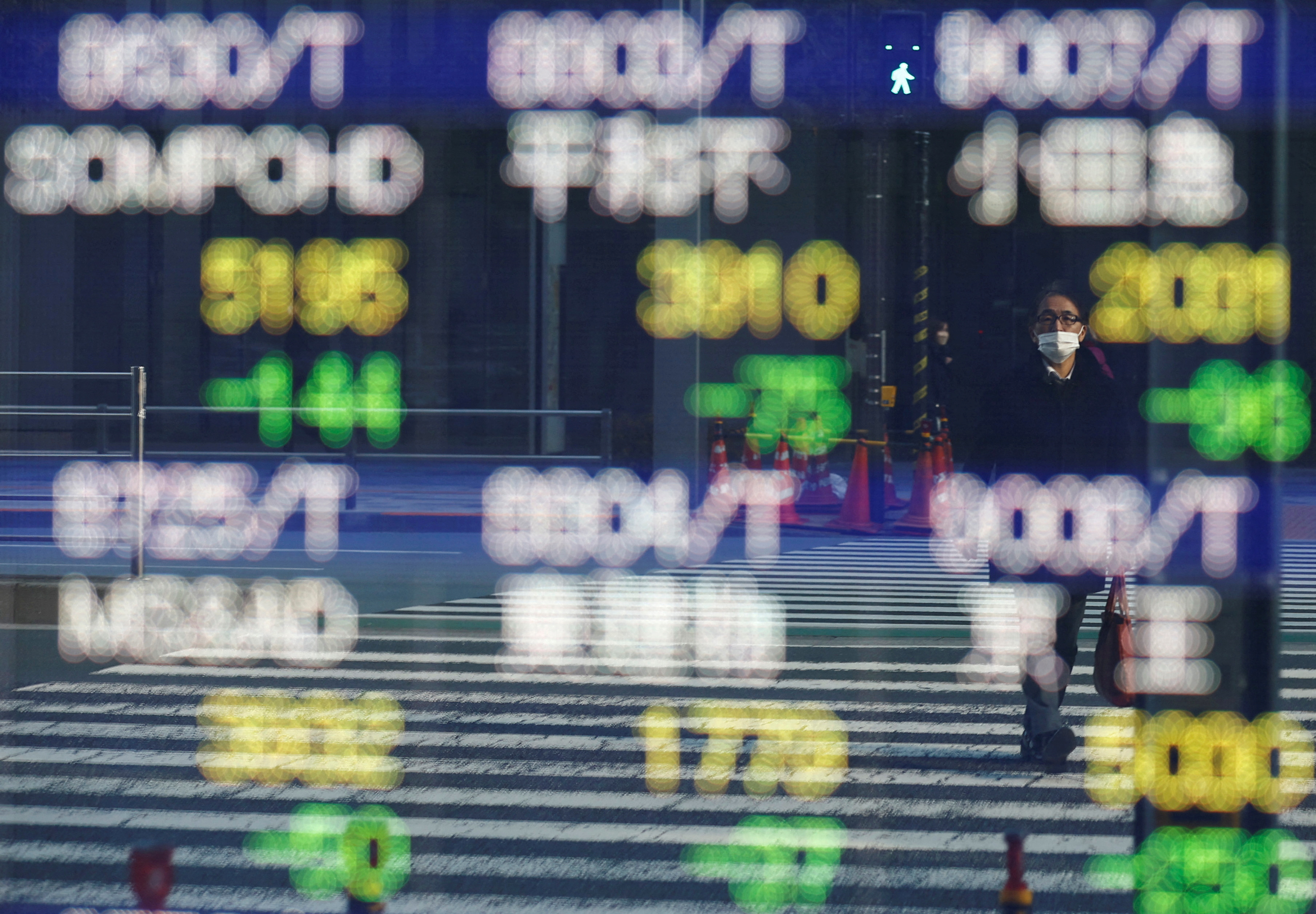 A man wearing a protective mask, amid the coronavirus disease (COVID-19) outbreak, is reflected on a screen showing various companies' stock prices outside a brokerage in Tokyo