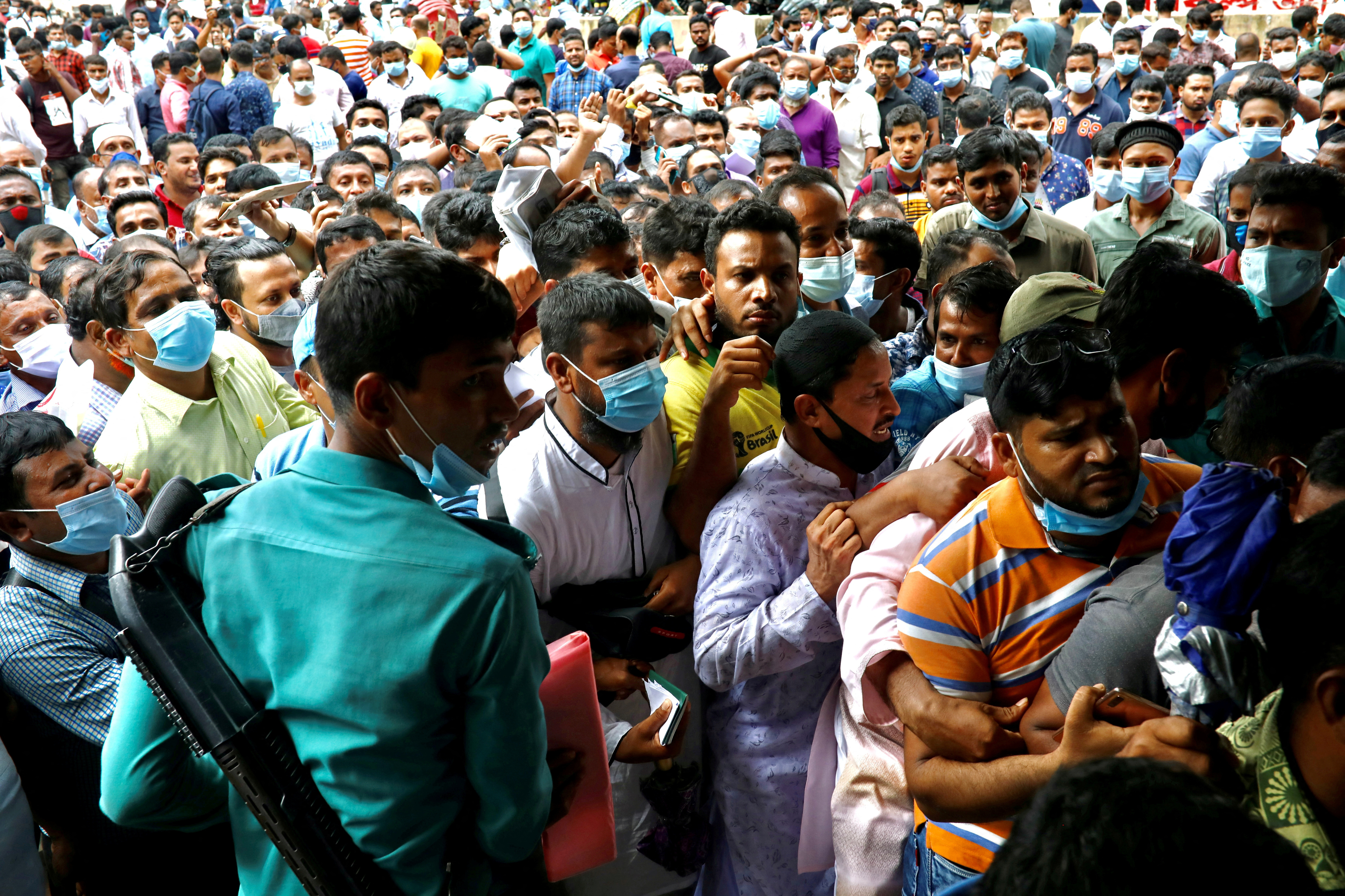 Police try to control the crowd as stranded Bangladeshi workers gather outside of the Biman Bangladesh Airlines office, demanding flight tickets to go back to Saudi Arabia, in Dhaka