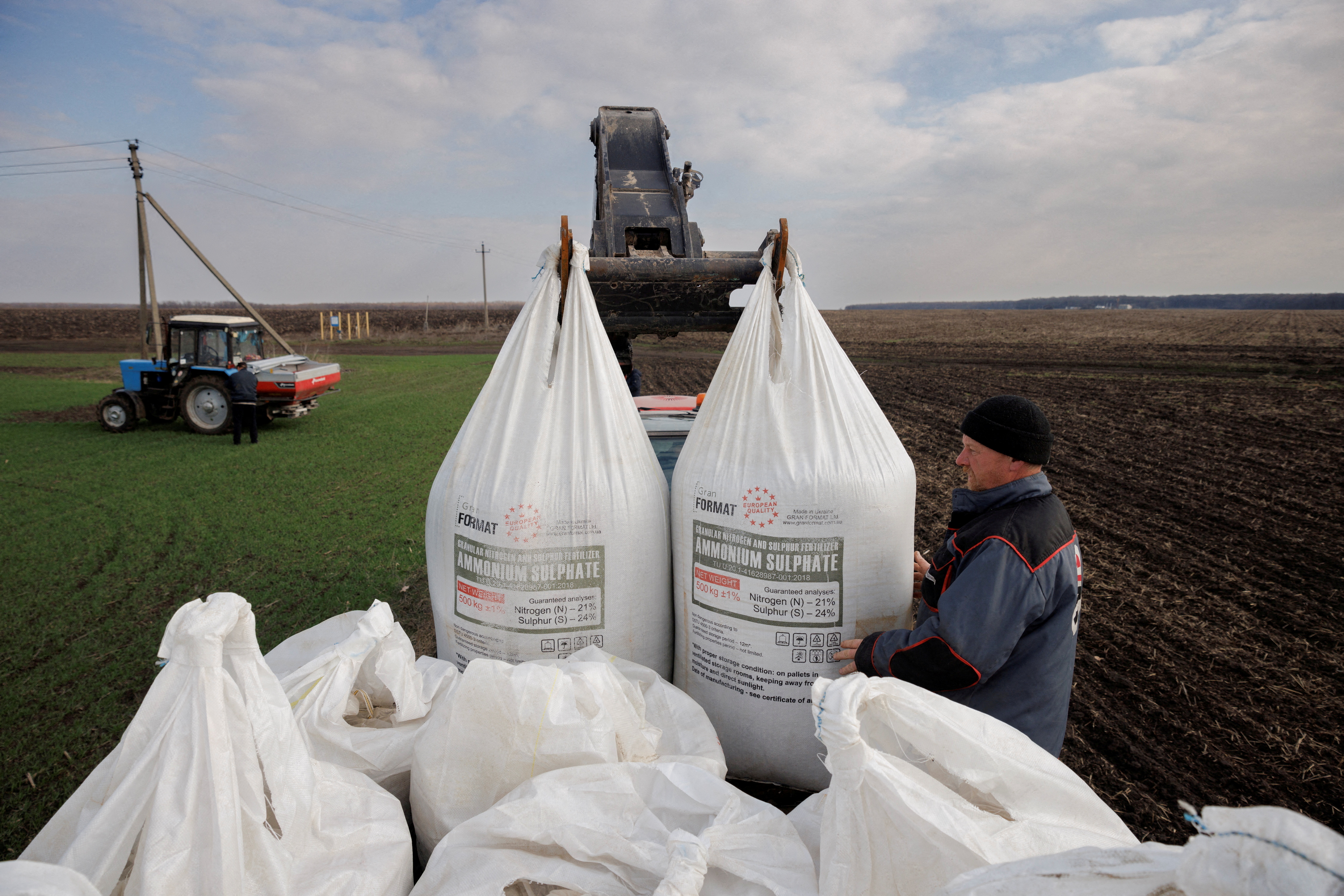 A local farm worker unloads Ukrainian-made fertiliser from a truck to use on a wheat field near the village of Yakovlivka after it was hit by an aerial bombardment outside Kharkiv.