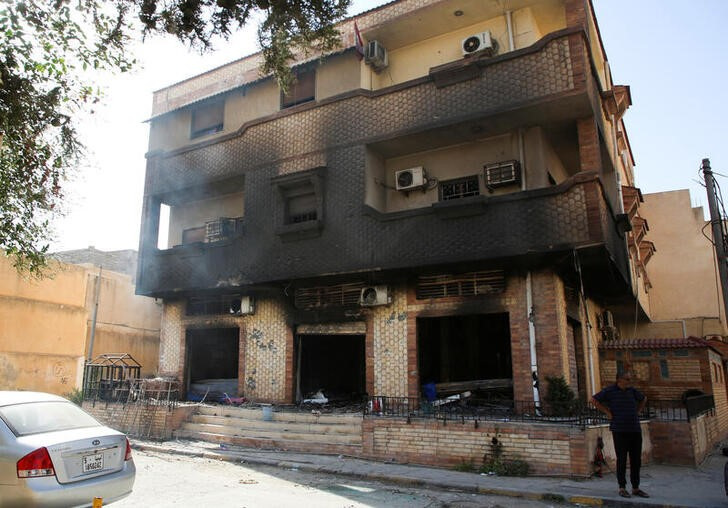 A man stands next to a building burned during yesterday's clashes in Tripoli
