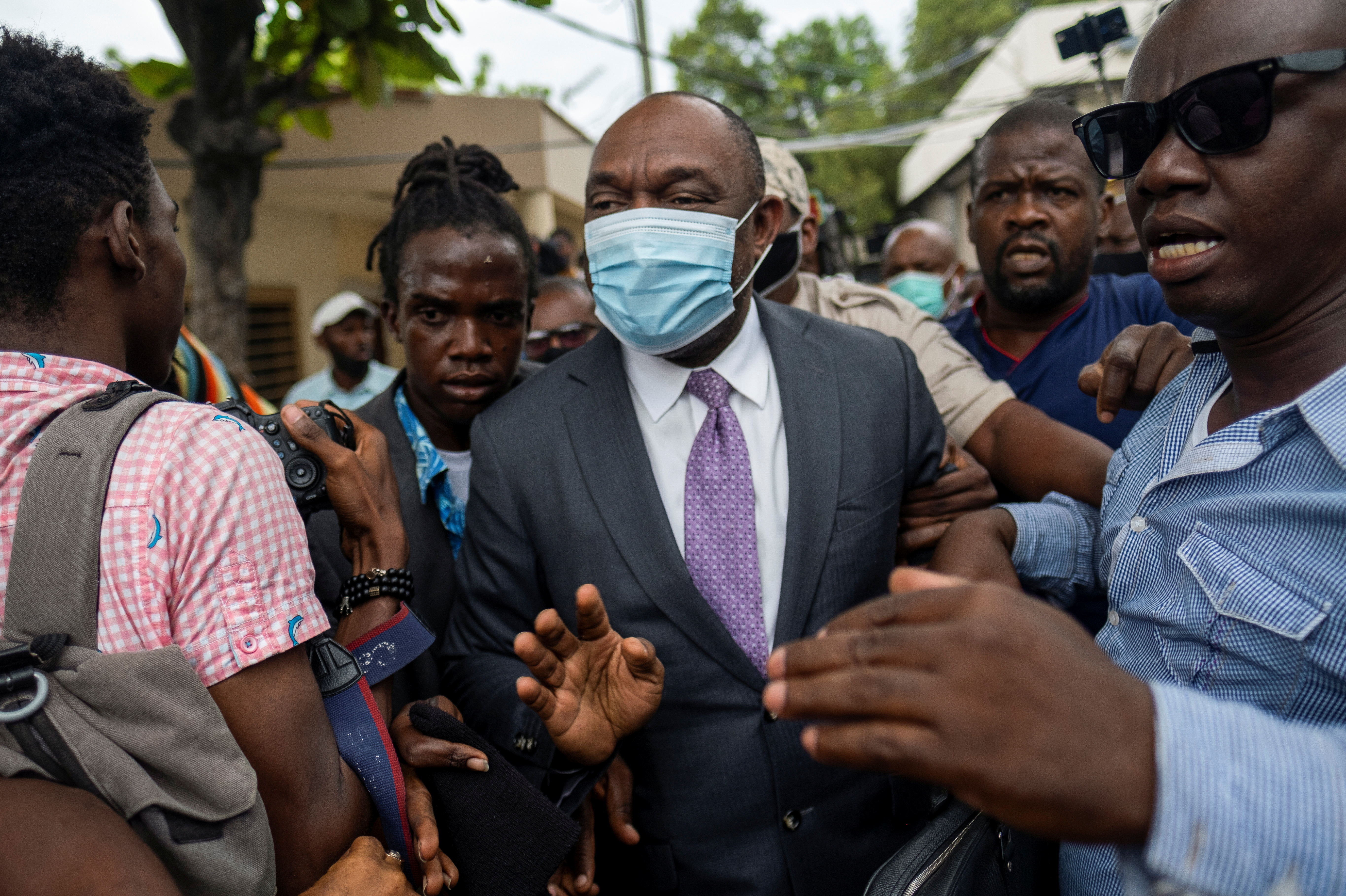 Former senator Youri Latortue wears a face mask as he is escorted by bodyguards outside the court house after a hearing following the assassination of President Jovenel Moise, in Port-au-Prince