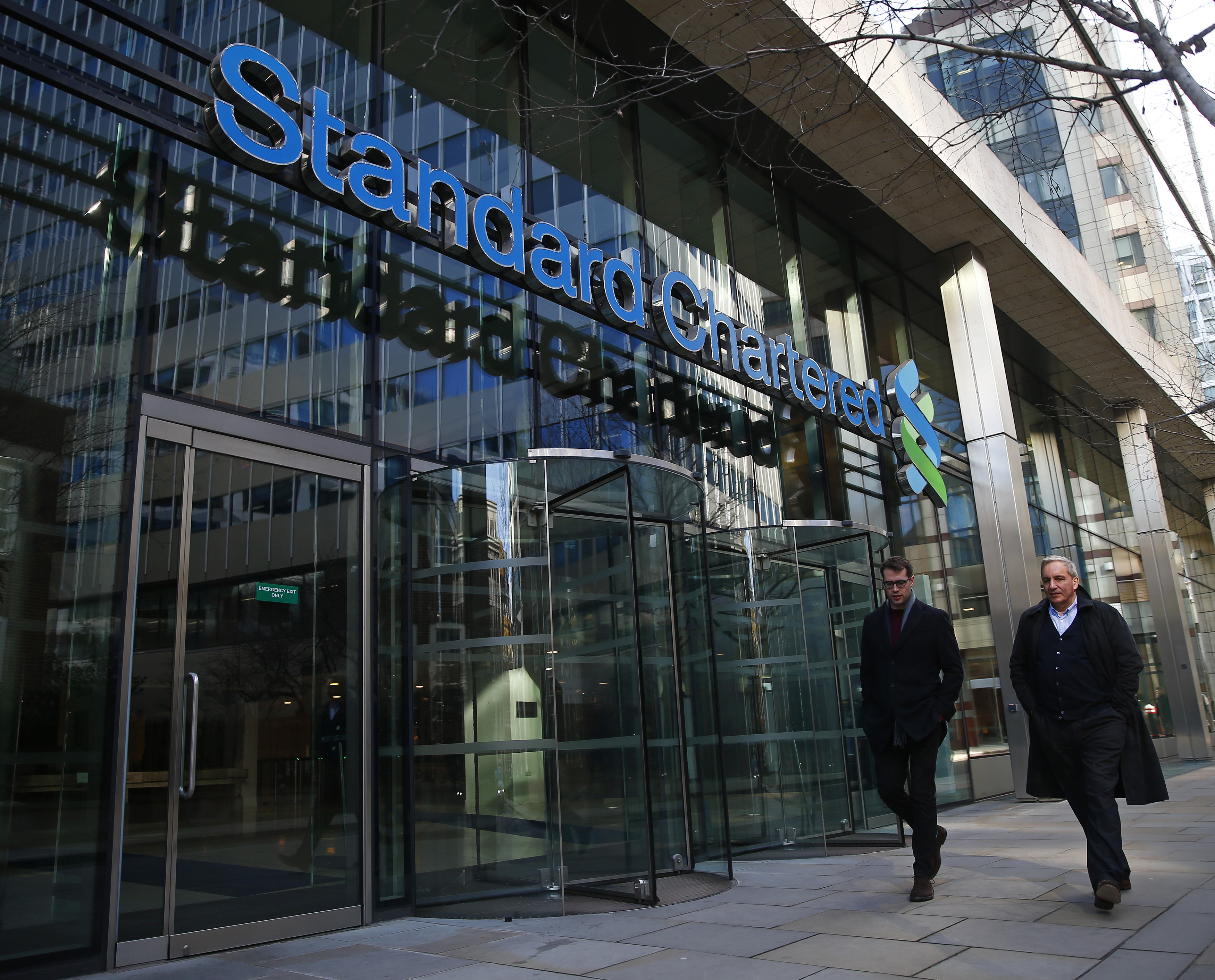 People walk past the head office of Standard Chartered bank in the City of London
