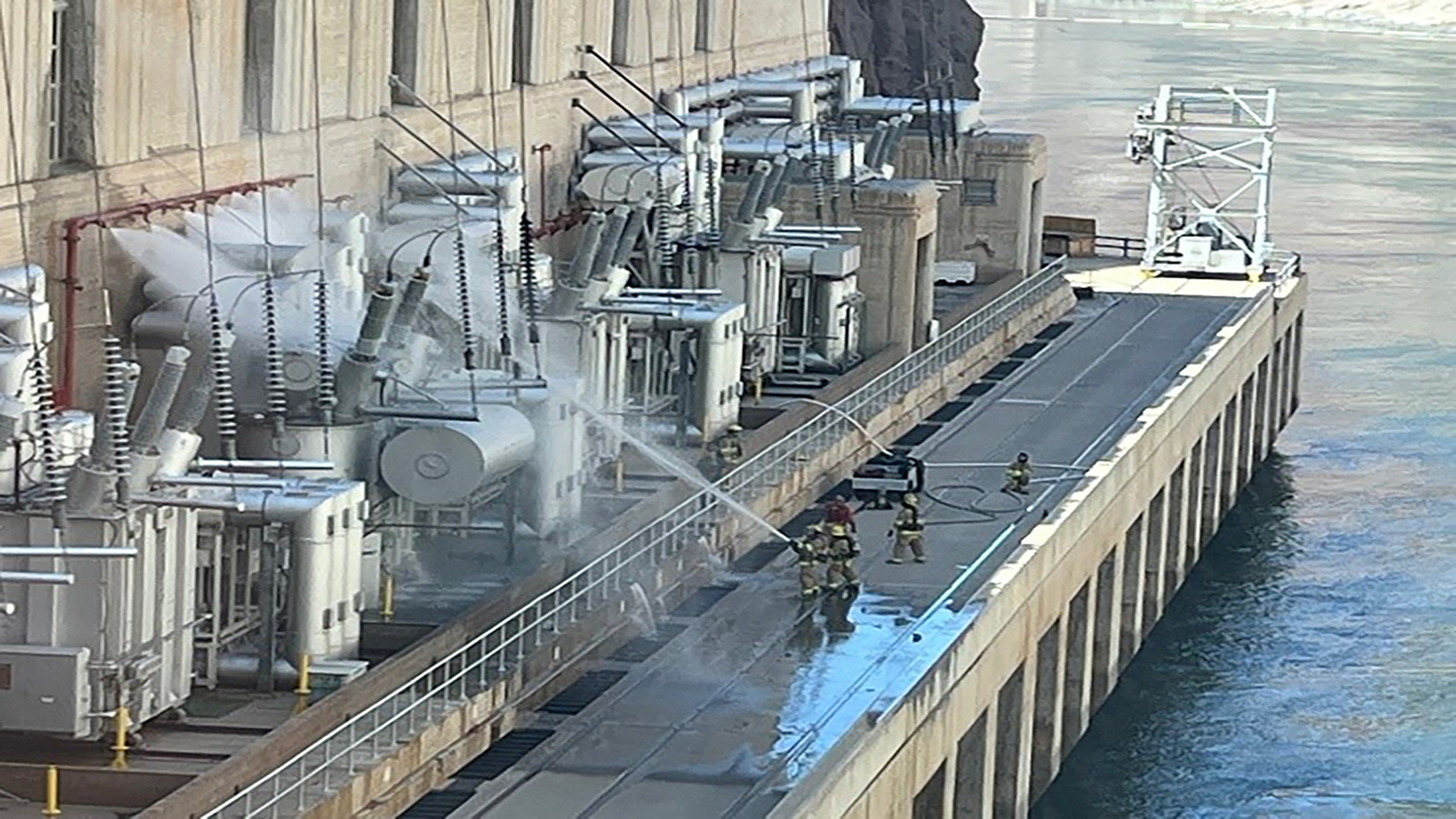 Firefighters pour water on electrical transformer equipment at the Hoover Dam