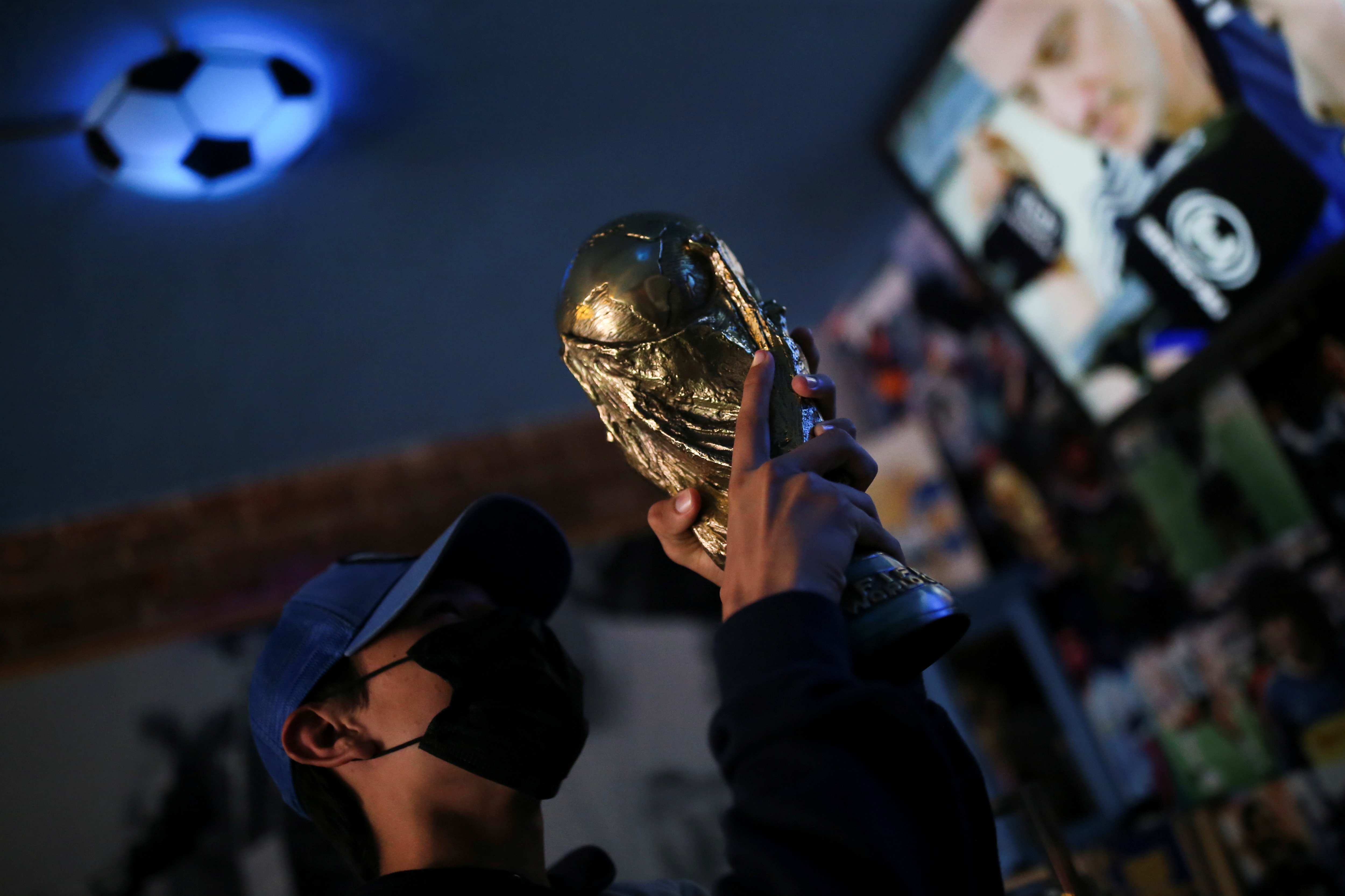 A fan holds up a replica of the World Cup trophy at the first Mexico's church in memory of soccer legend Diego Armando Maradona in San Andres Cholula