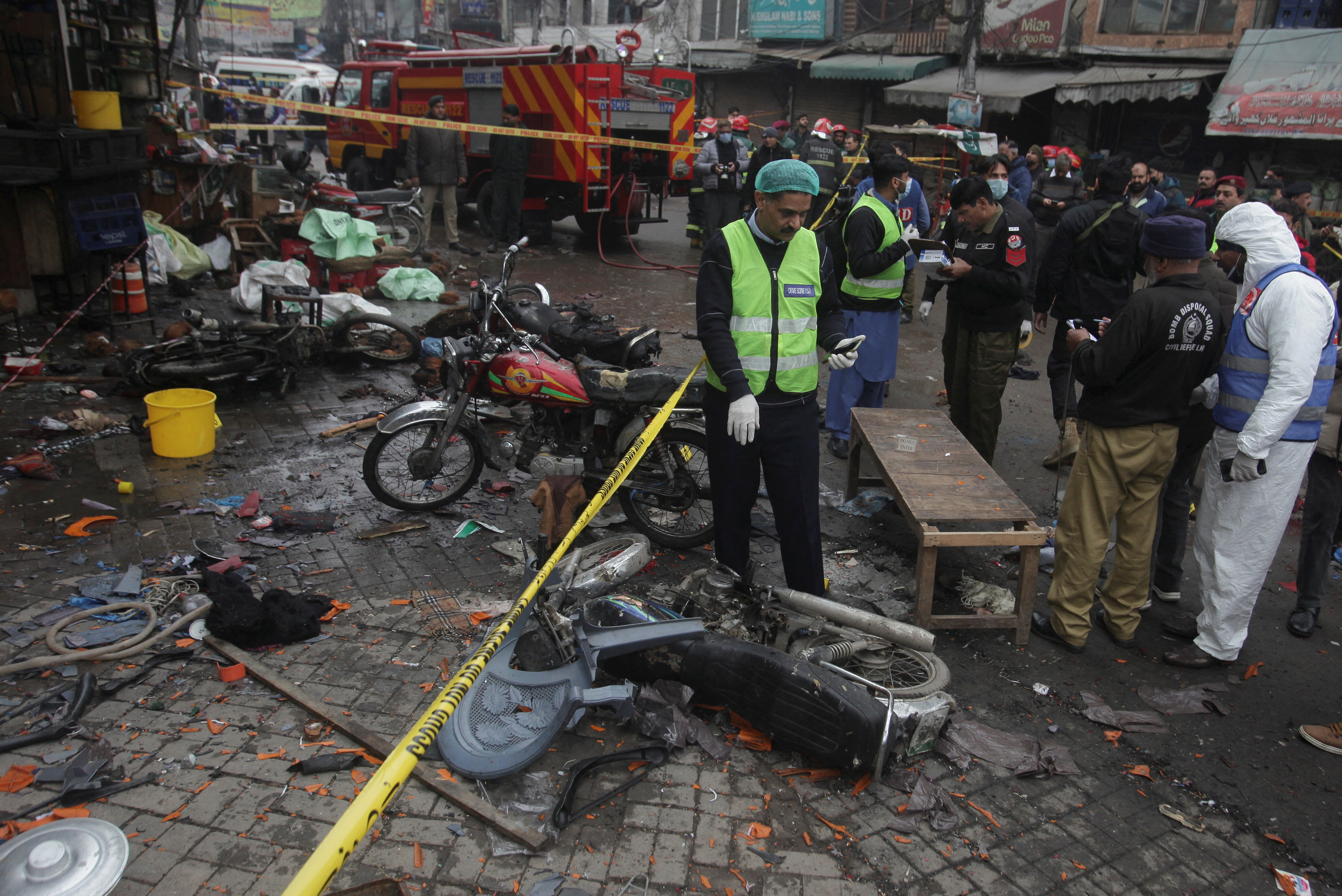 Members of crime scene unit and bomb disposal team gather after a blast in Lahore