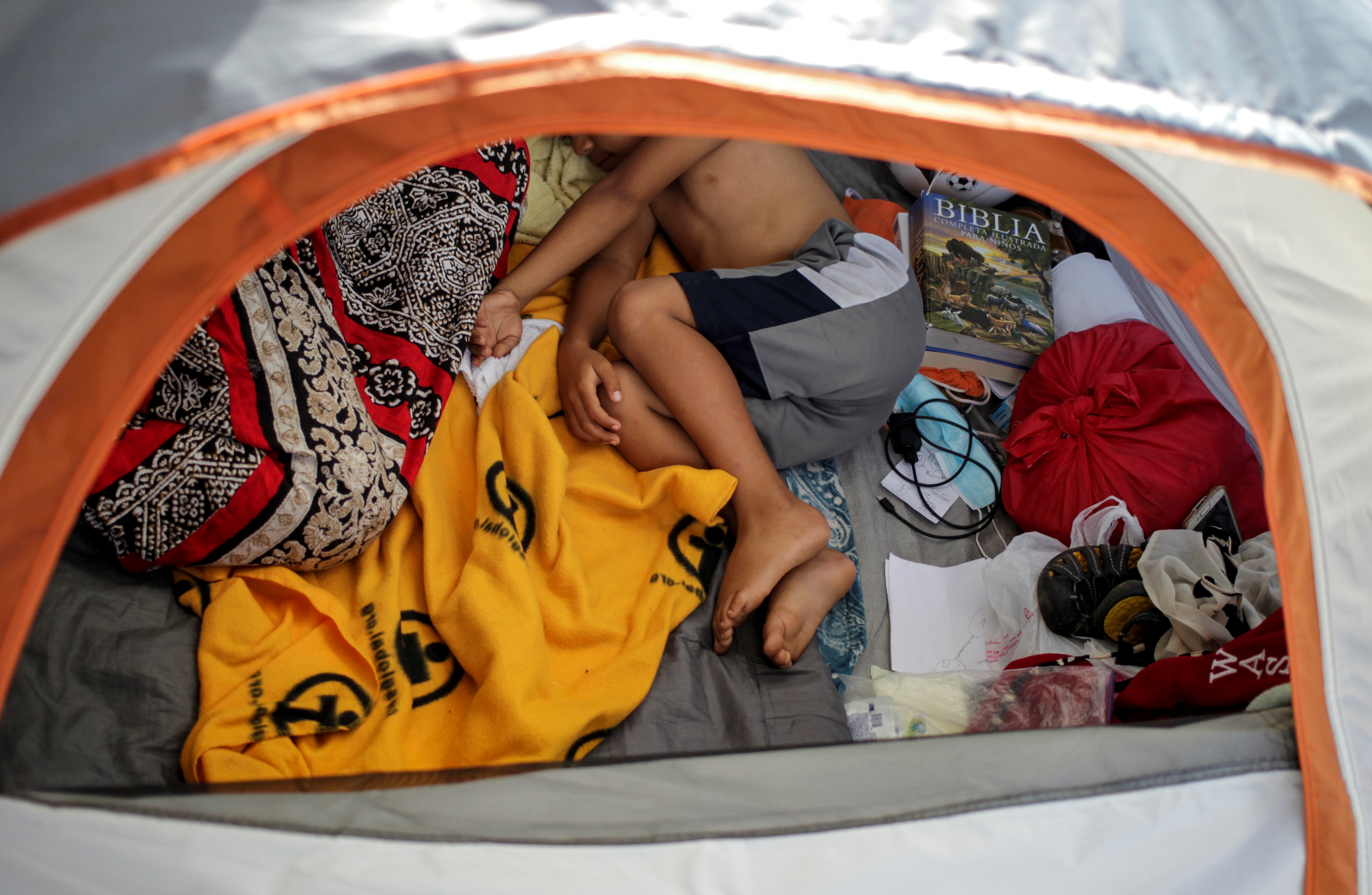 An asylum-seeking migrant youth, who was apprehended and returned to Mexico under Title 42 after crossing the border from Mexico into the U.S., rests in a public square where hundreds of migrants live in tents, in Reynosa