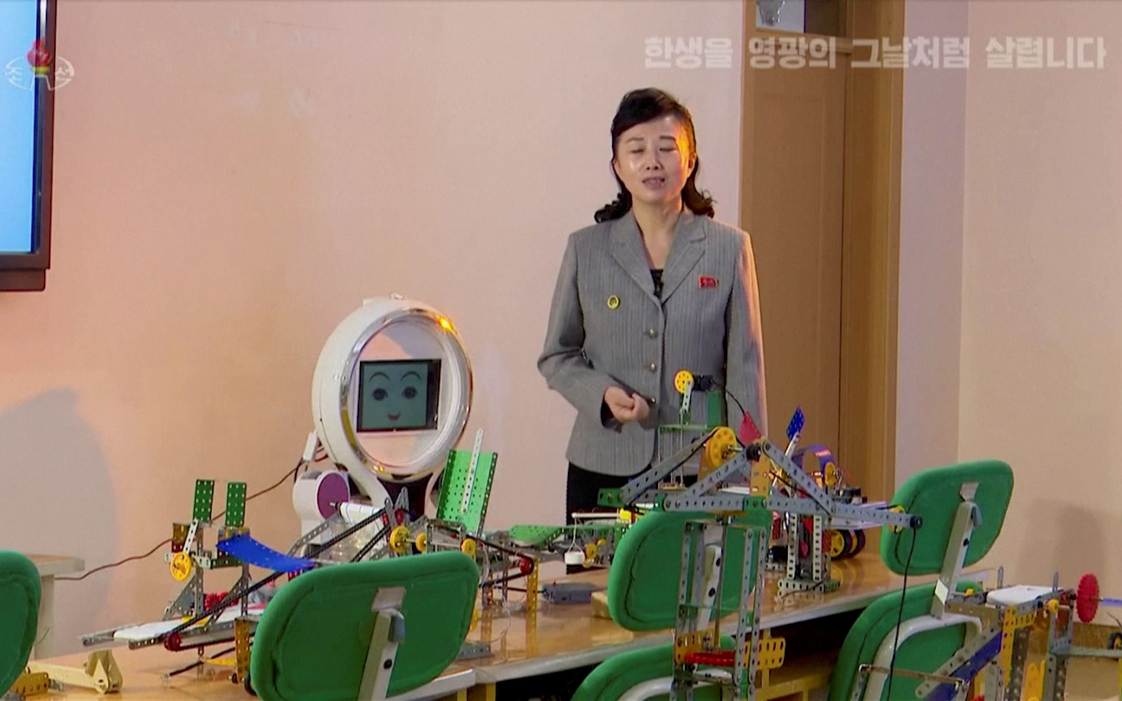 Woman stands next to a robot, in Pyongyang