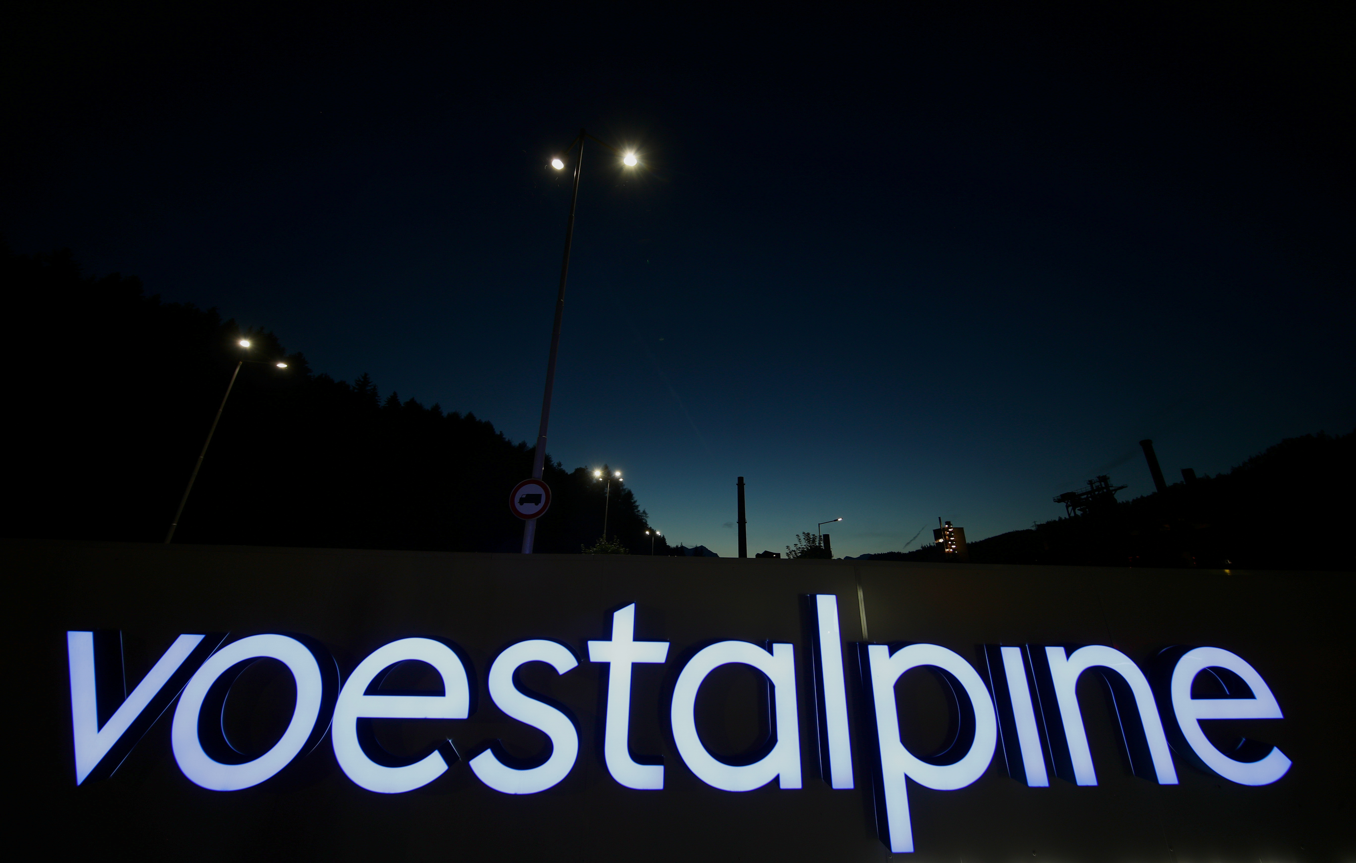 An illuminated logo of steelmaker Voestalpine stands in front of the steel plant Donawitz in Leoben