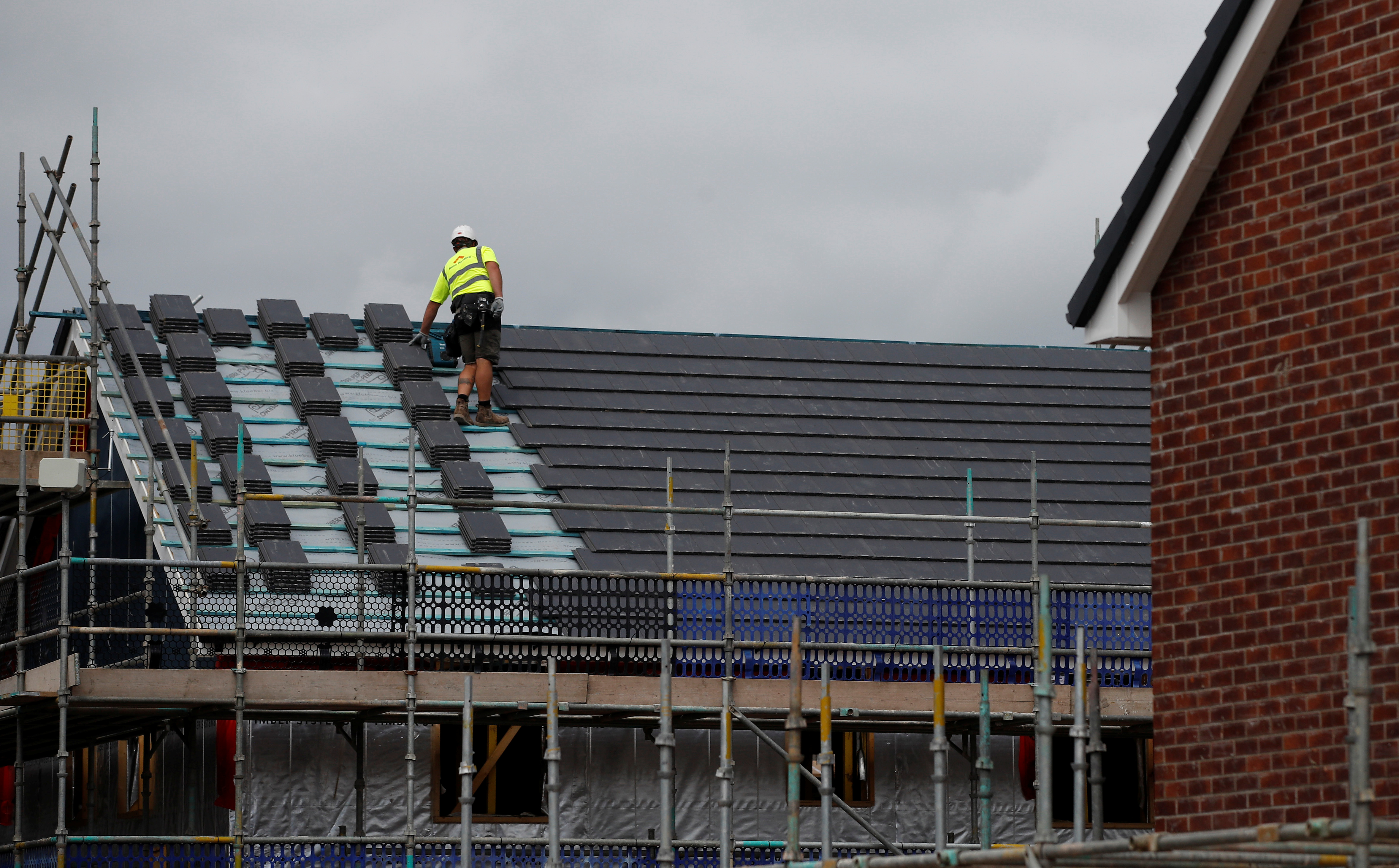A scaffolder works on a new Barratt Homes housing development near Warrington, Britain, August 6, 2020. REUTERS/Phil Noble