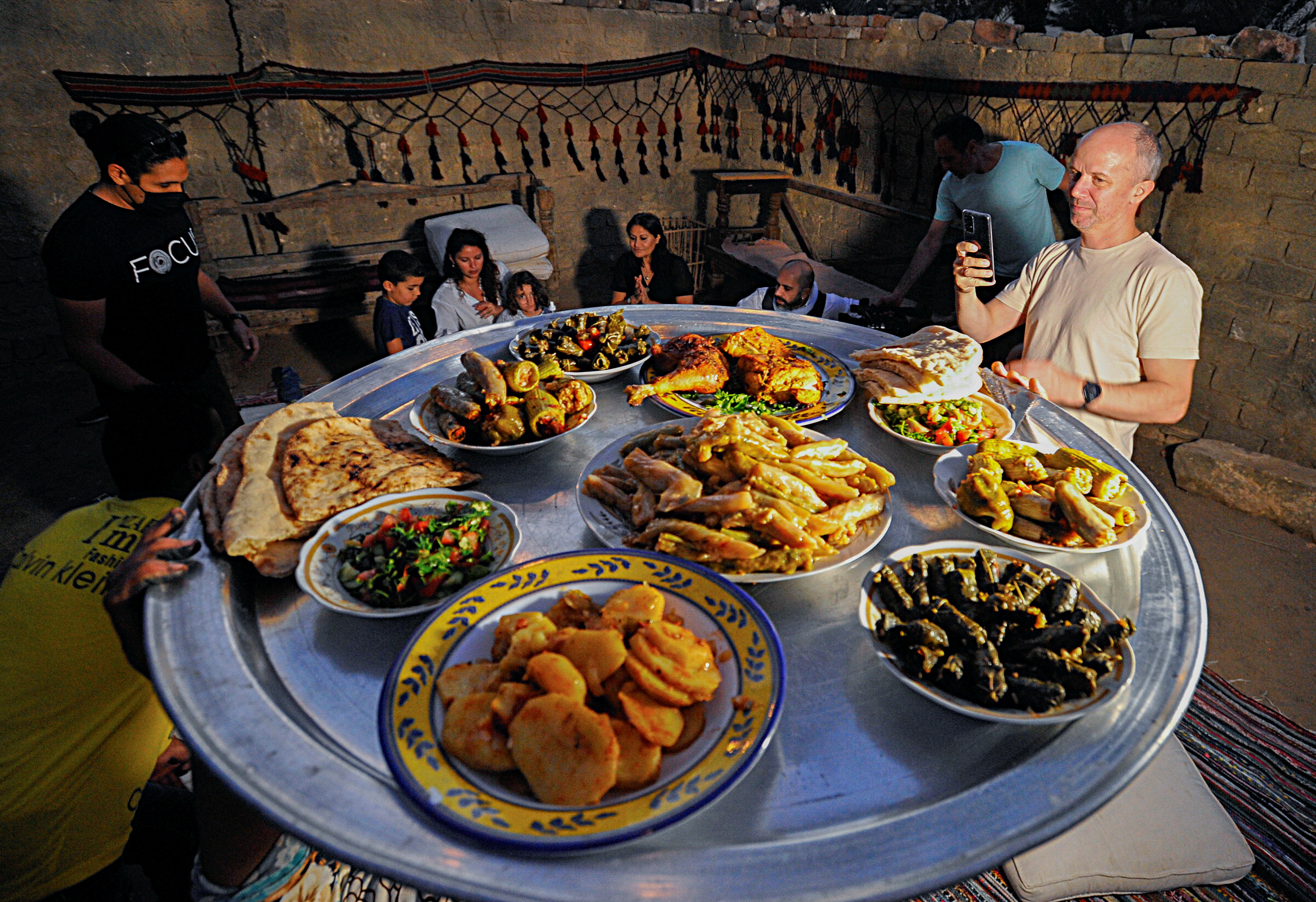 Tourists are seen next to a meal made by Saqqara residents, who sell food to improve their living conditions in thier village