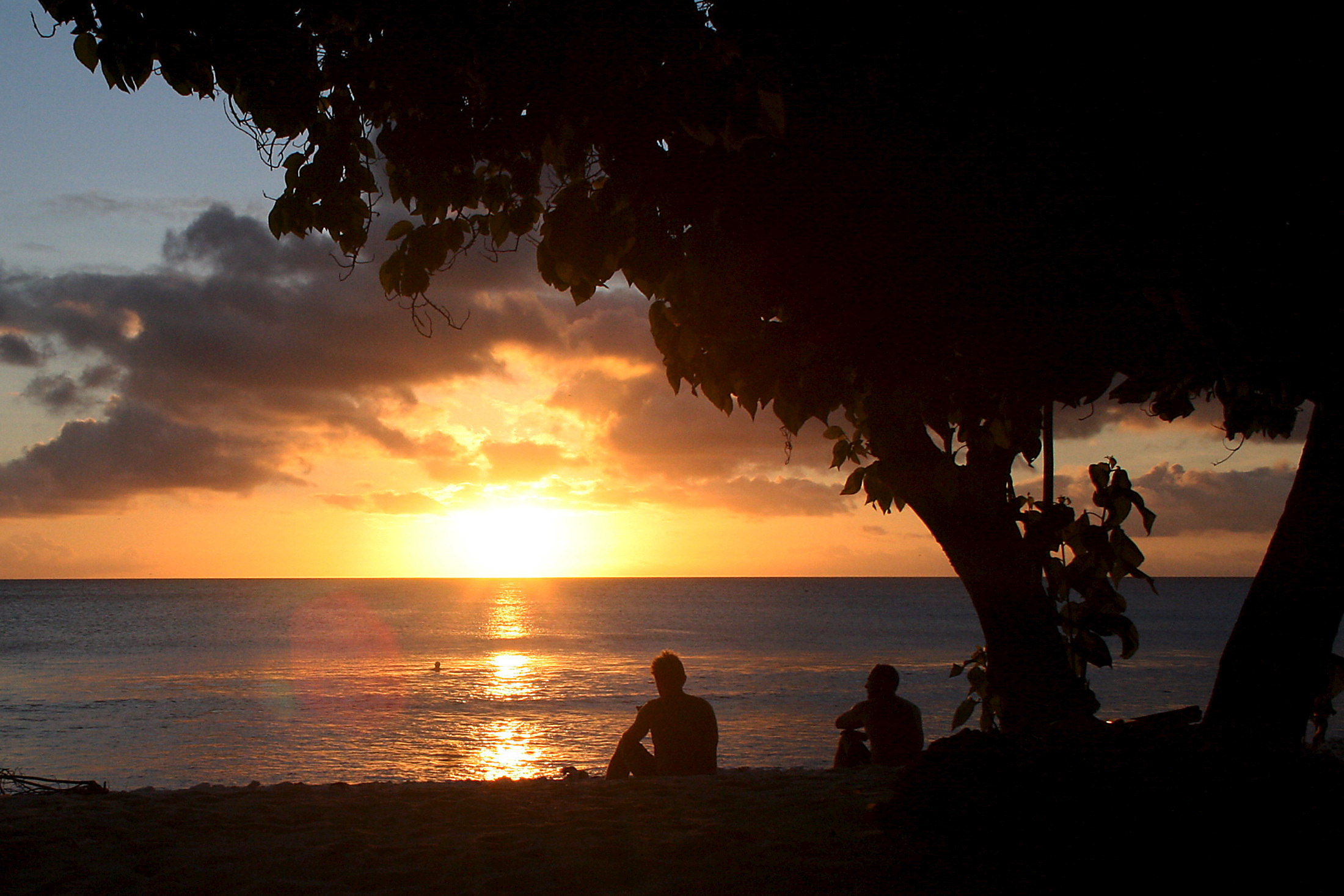 Les surfeurs regardent le soleil se coucher après avoir surfé le long de la côte de l'île de Kiritimati, qui fait partie de la nation insulaire du Pacifique de Kiribati