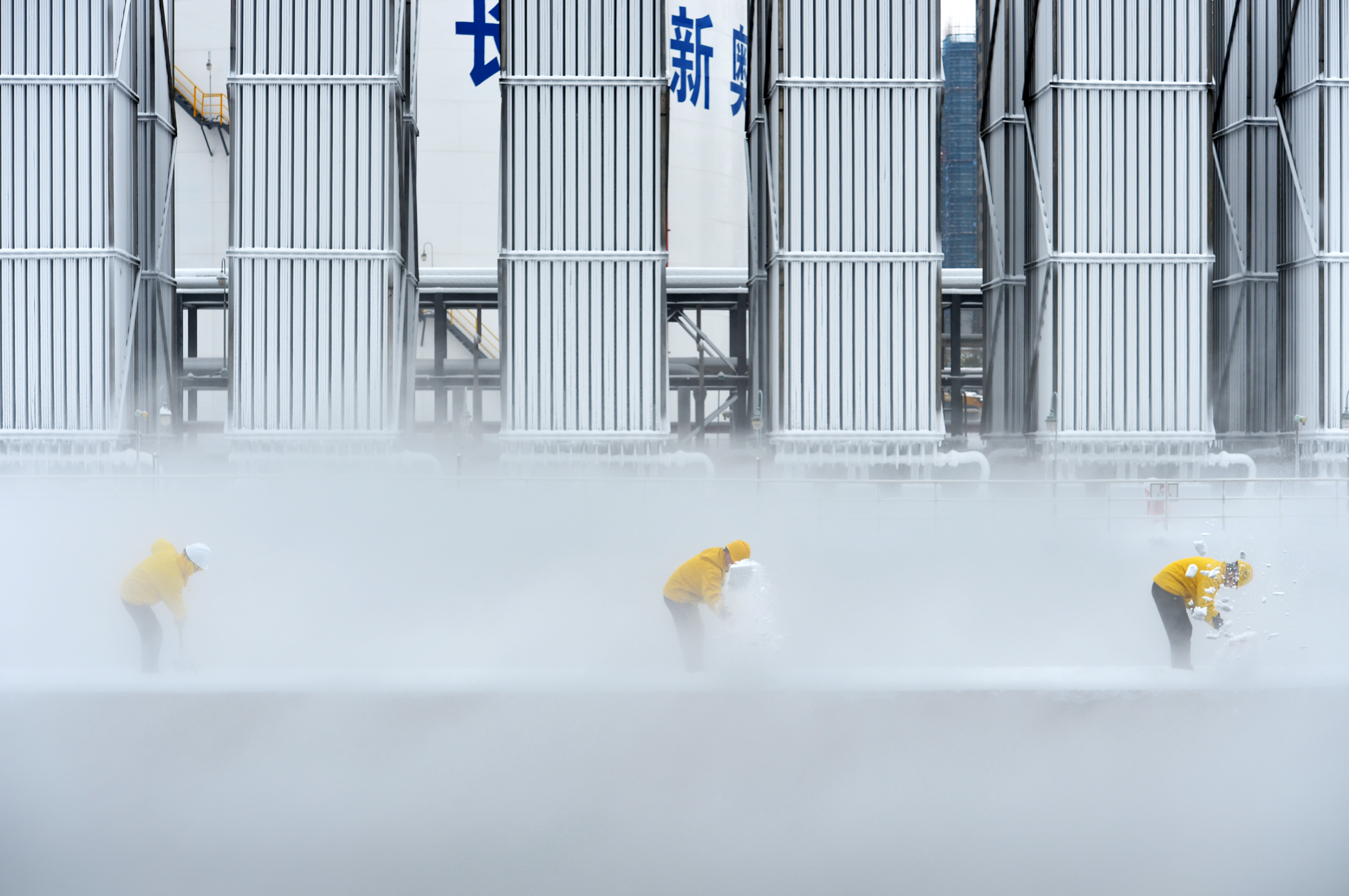 Workers remove snow at a liquefied natural gas (LNG) facility of ENN Group in Changsha