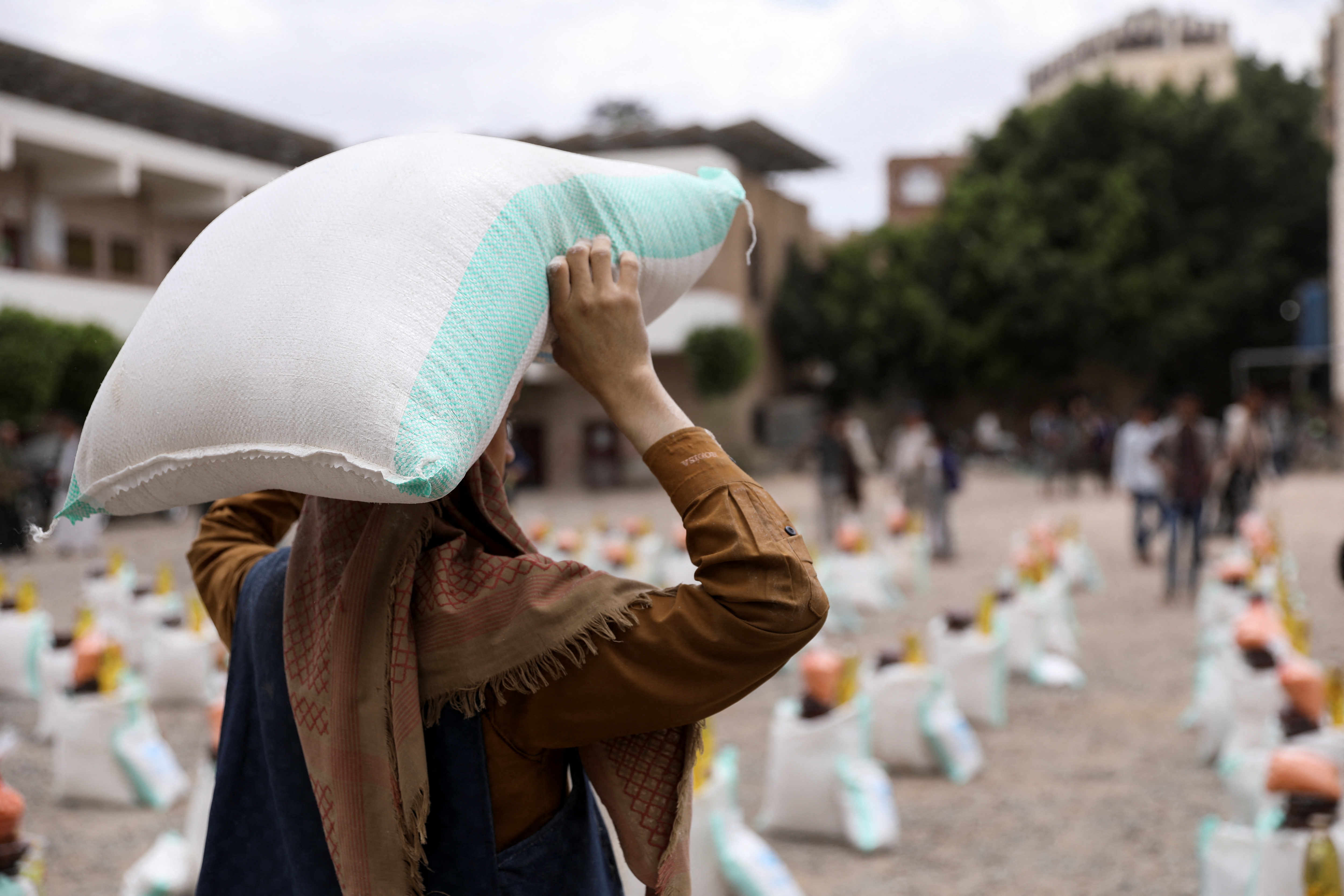 Worker carries a sack of wheat flour during the distribution of food aid by the local charity, Mona Relief, in Sanaa
