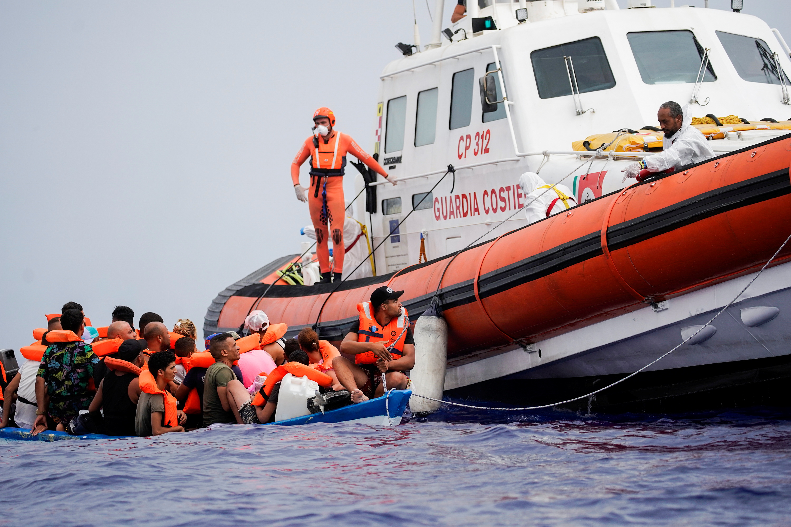 Members of Italian Guardia Costiera prepare to bring on board the migrants of a wooden boat near the island of Lampedusa, in the Mediterranean Sea, September 1, 2021. REUTERS/Juan Medina