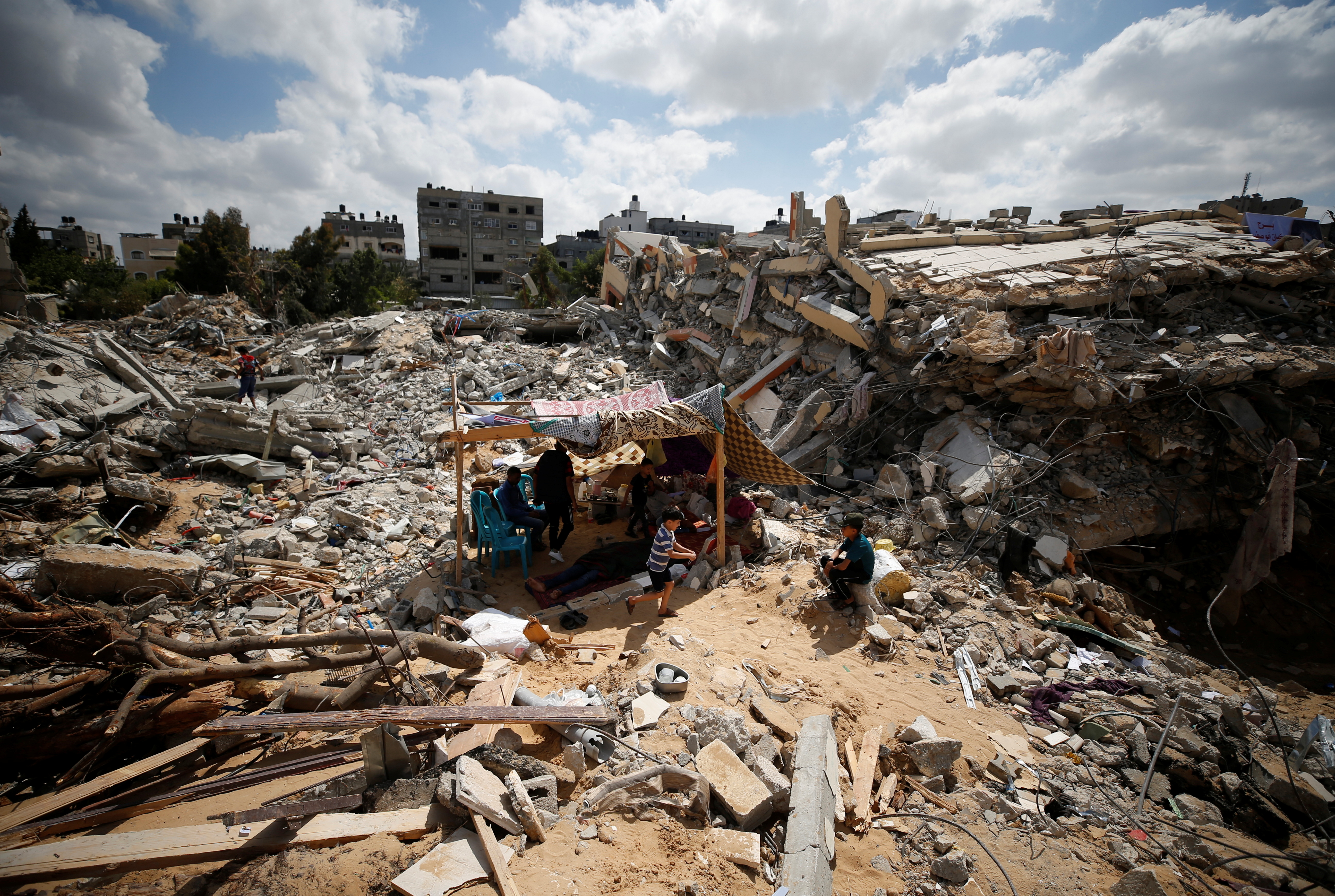 Οι Παλαιστίνιοι κάθονται σε μια αυτοσχέδια σκηνή ανάμεσα στα ερείπια των σπιτιών τους που καταστράφηκαν από ισραηλινές αεροπορικές επιδρομές κατά τη διάρκεια των μαχών Ισραήλ-Χαμάς στη Γάζα, 23 Μαΐου 2021. REUTERS/Mohammed Salem