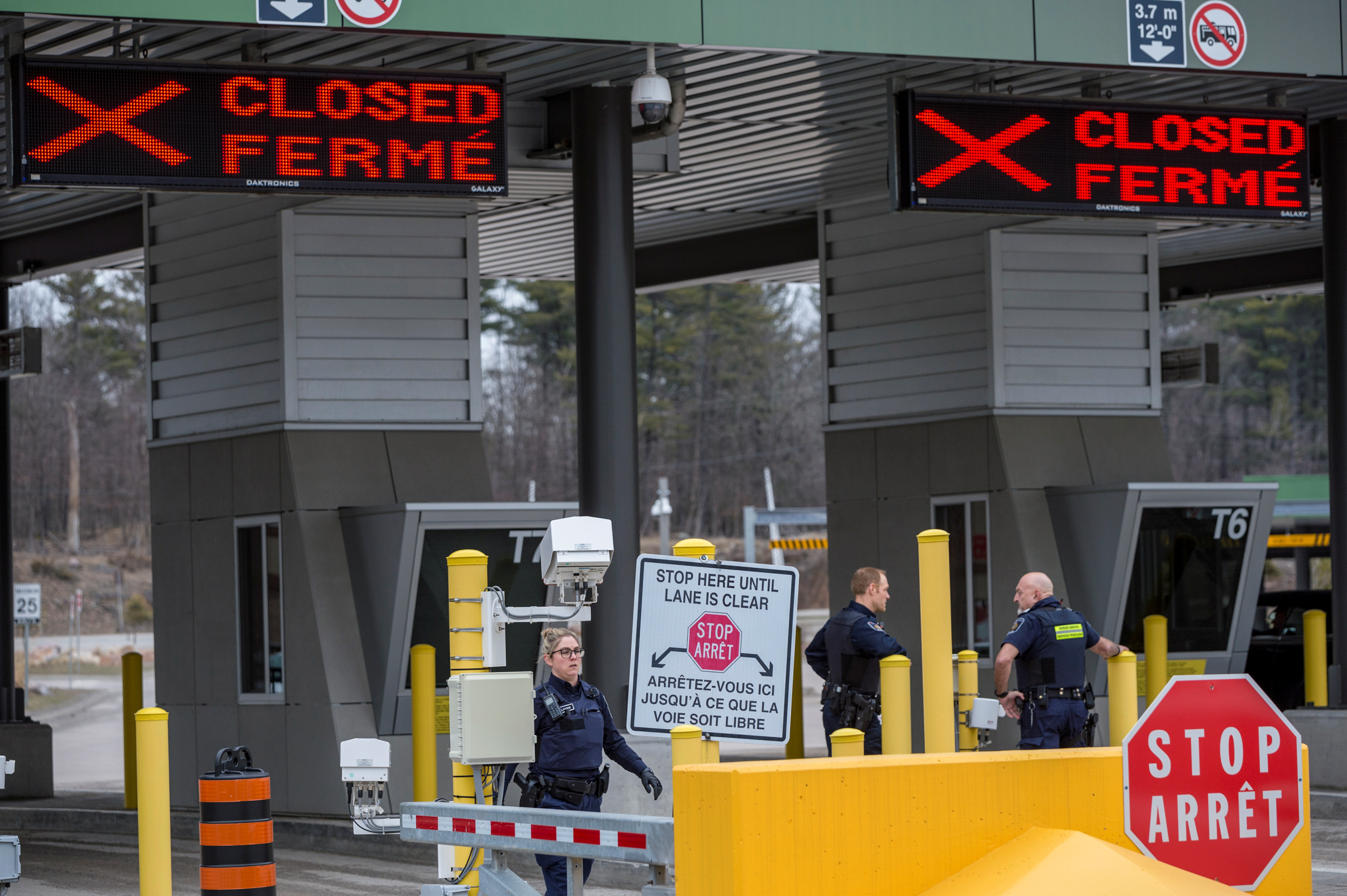 Canadian Border Services Agency officers stand in front of two closed Canadian border checkpoints in Lansdowne