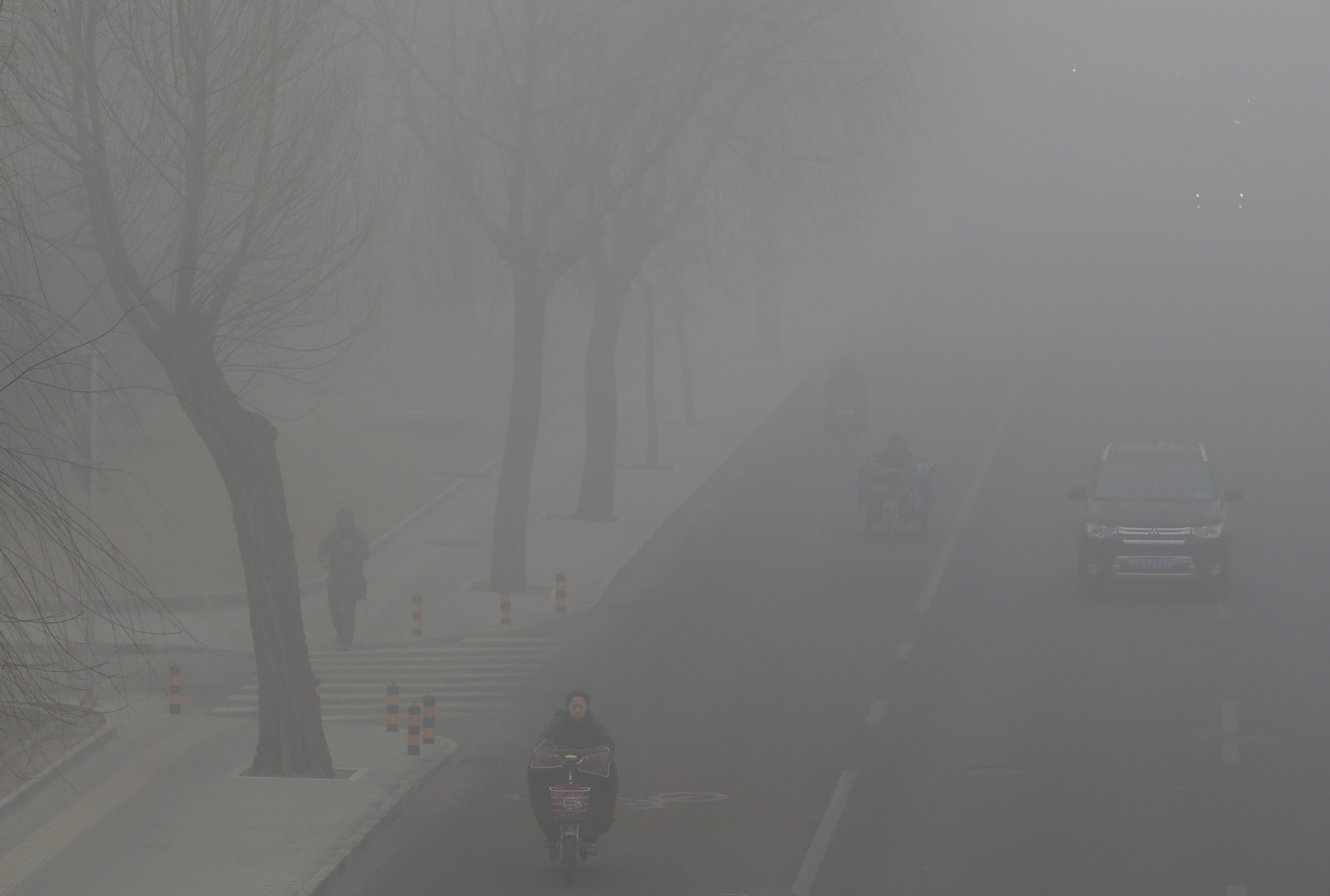 People drive and ride amid the smog in Beijing