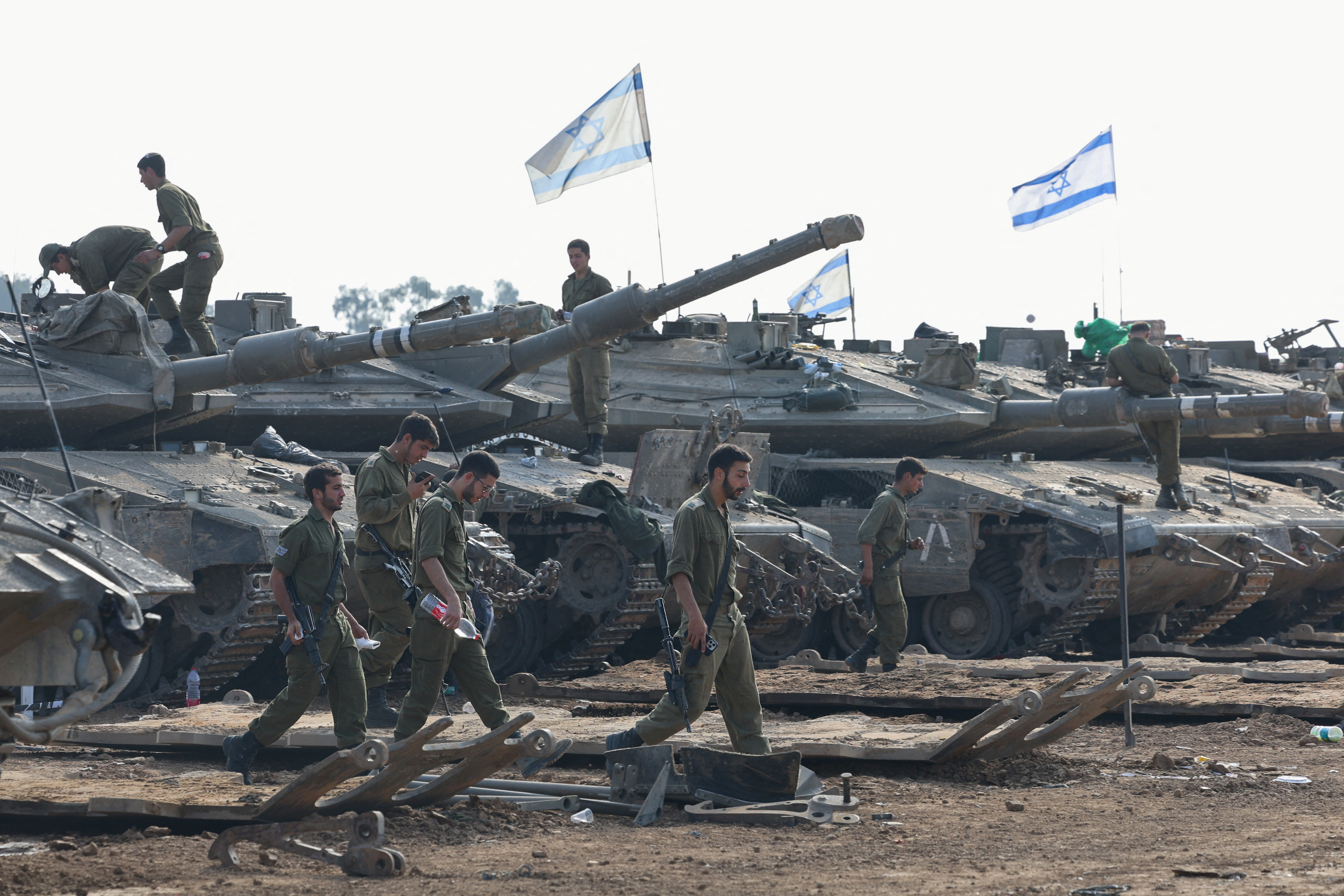 Israeli soldiers walk next to tanks, near the Israel-Gaza border