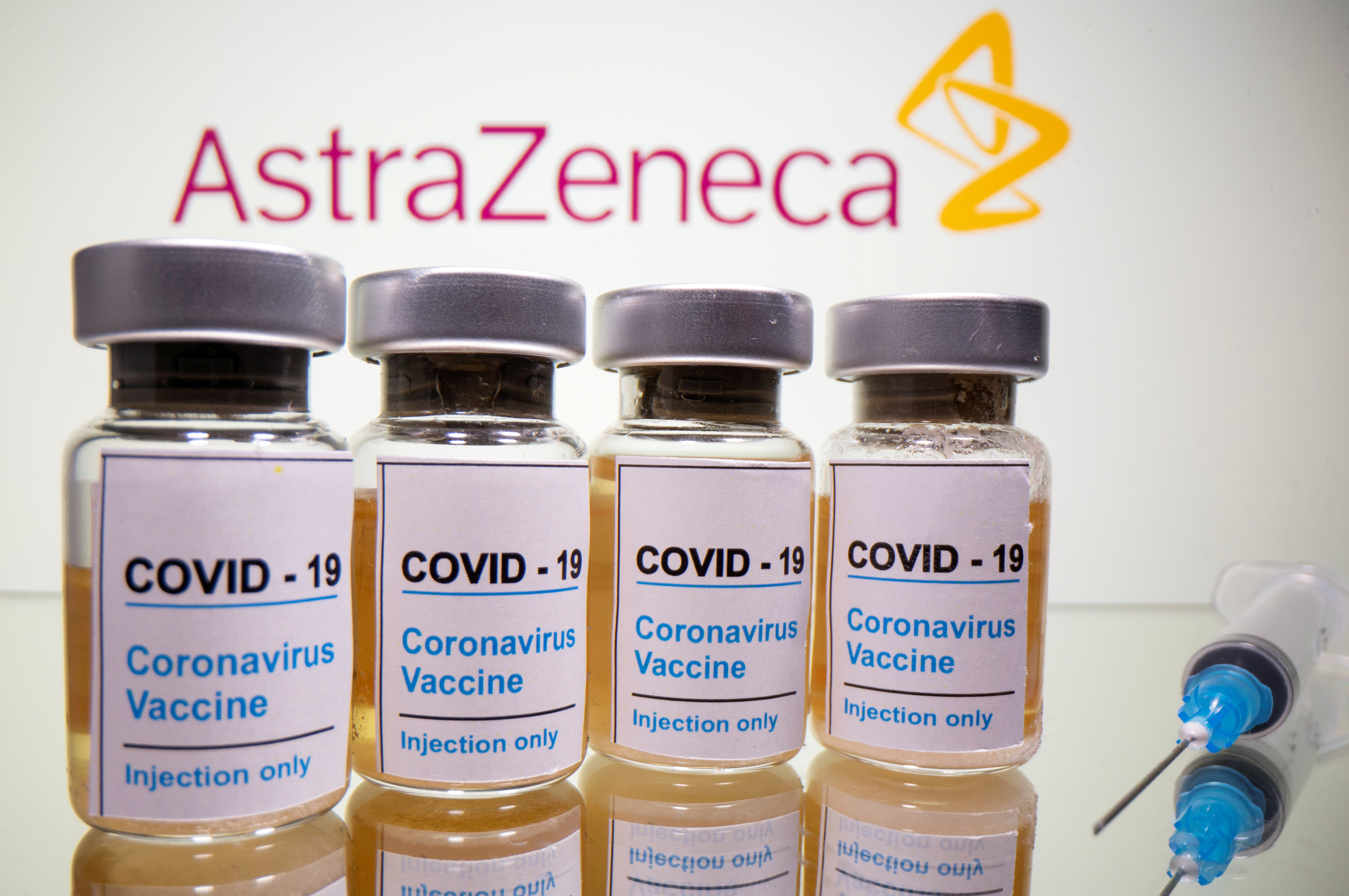 Vials and medical syringe are seen in front of AstraZeneca logo in this illustration
