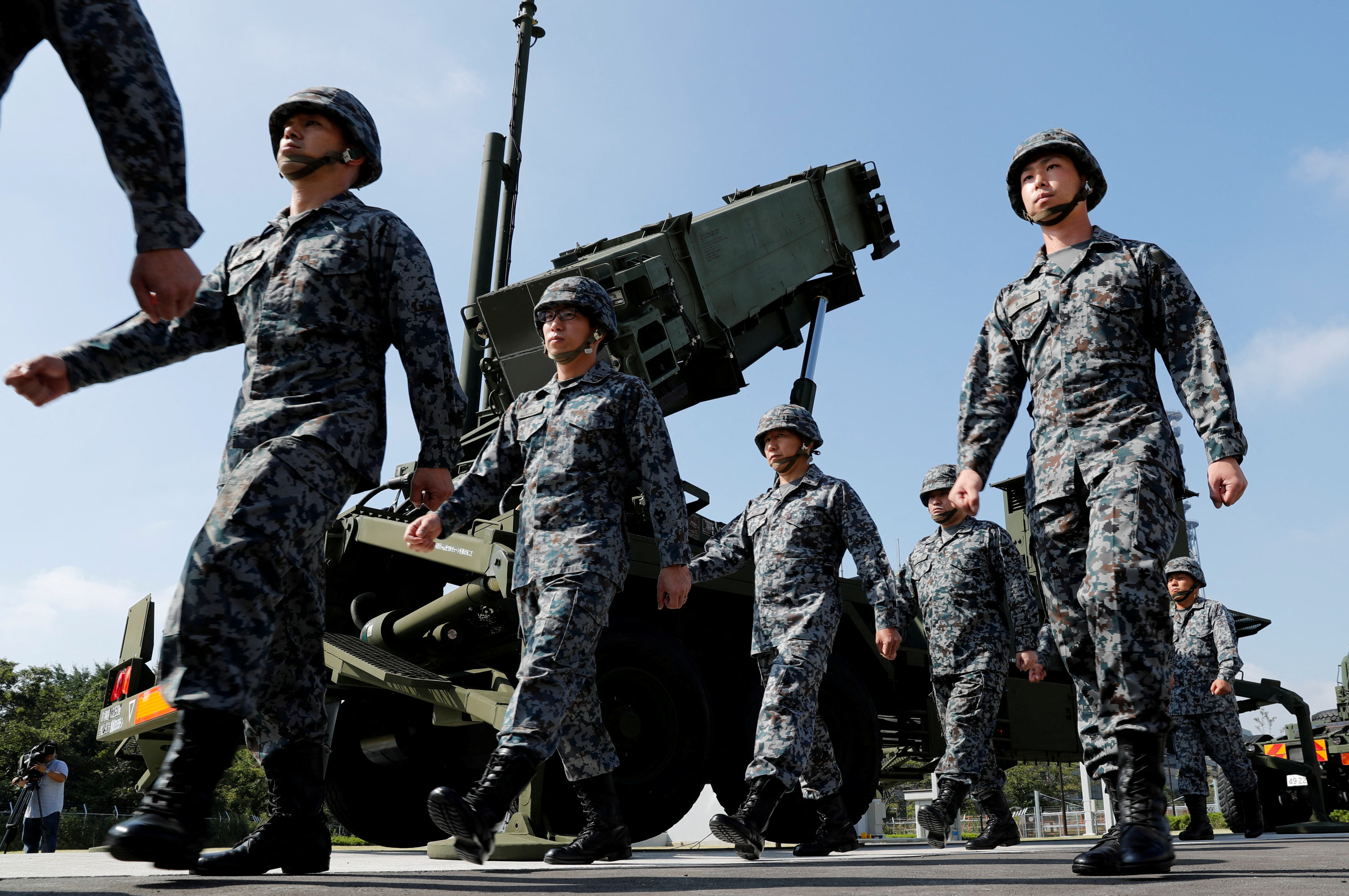 Japan Self-Defense Forces (JSDF) soldiers walk past a Patriot Advanced Capability-3 (PAC-3) missile unit after Japan's Chief Cabinet Secretary Yoshihide Suga (L) reviews the unit at the Defense Ministry in Tokyo