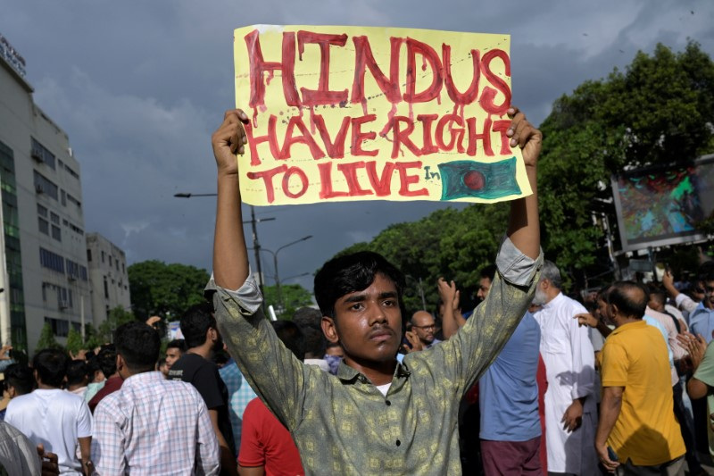 A demonstrator displays a placard during a protest against what they say violence against Hindu communities during ongoing unrest, in Dhaka