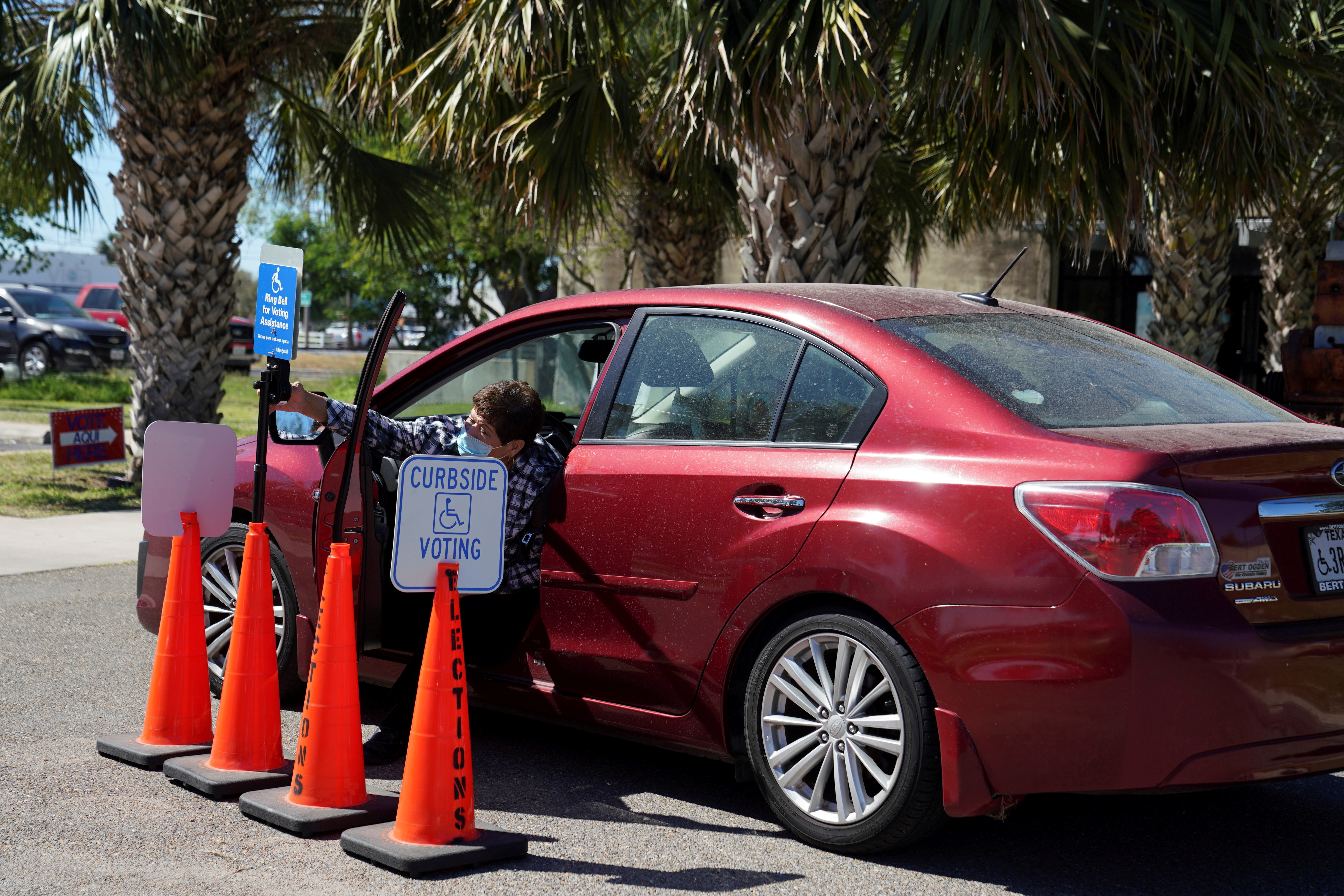 A woman rings the bell to get assistance through a curbside polling site in McAllen
