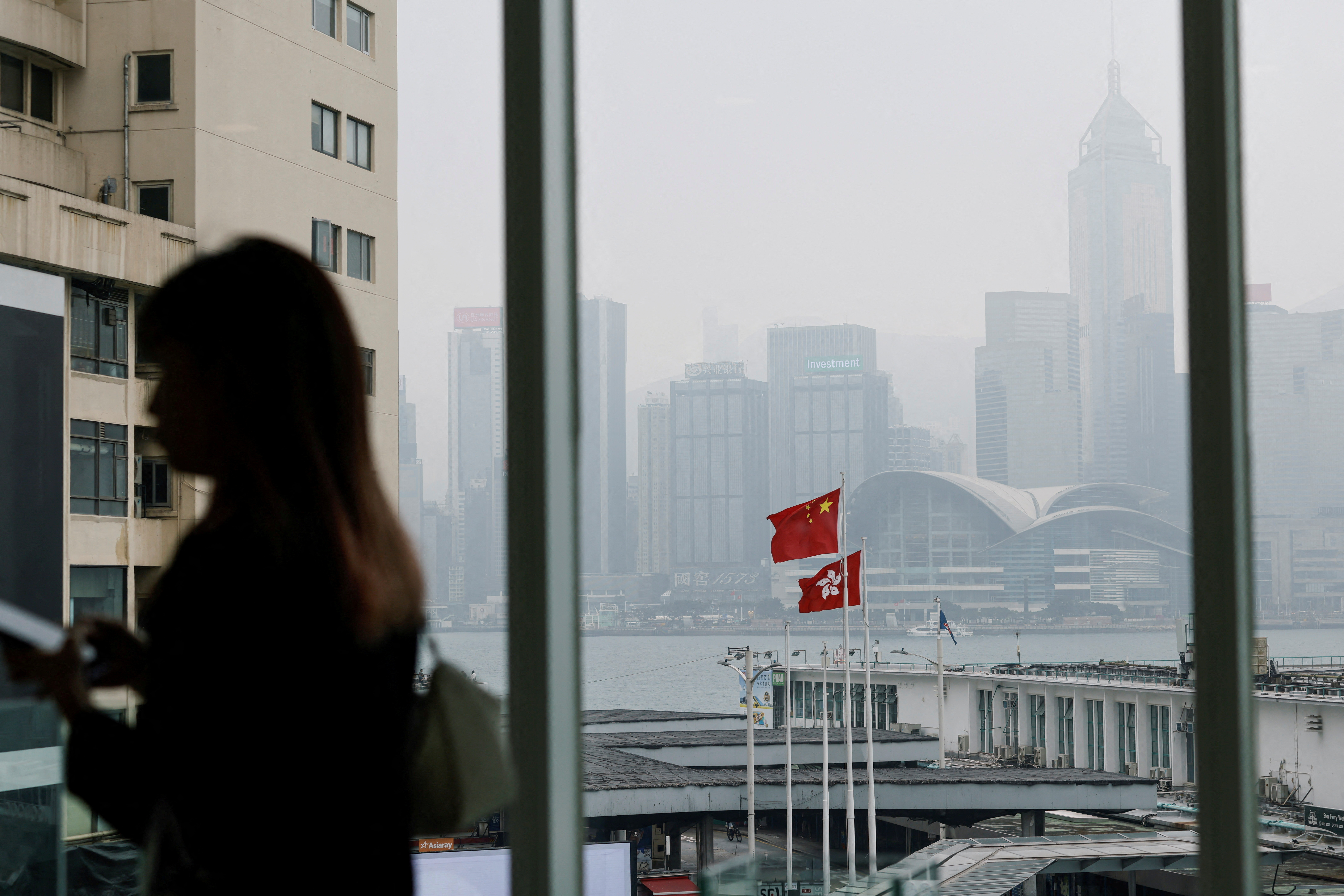 Chinese and Hong Kong flags are seen at the waterfront during a foggy day in Hong Kong