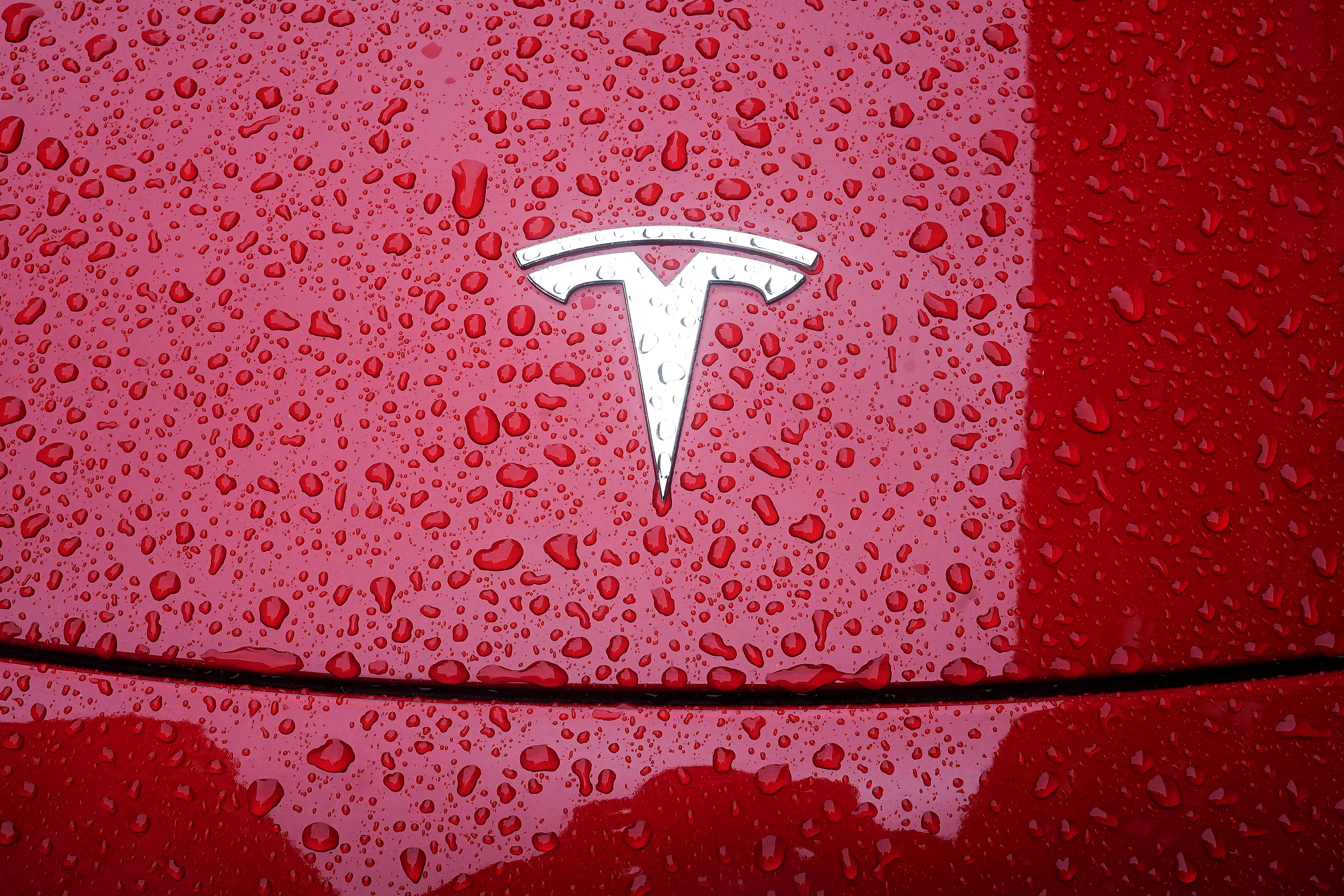 A Tesla logo is pictured on a car in the rain in New York City