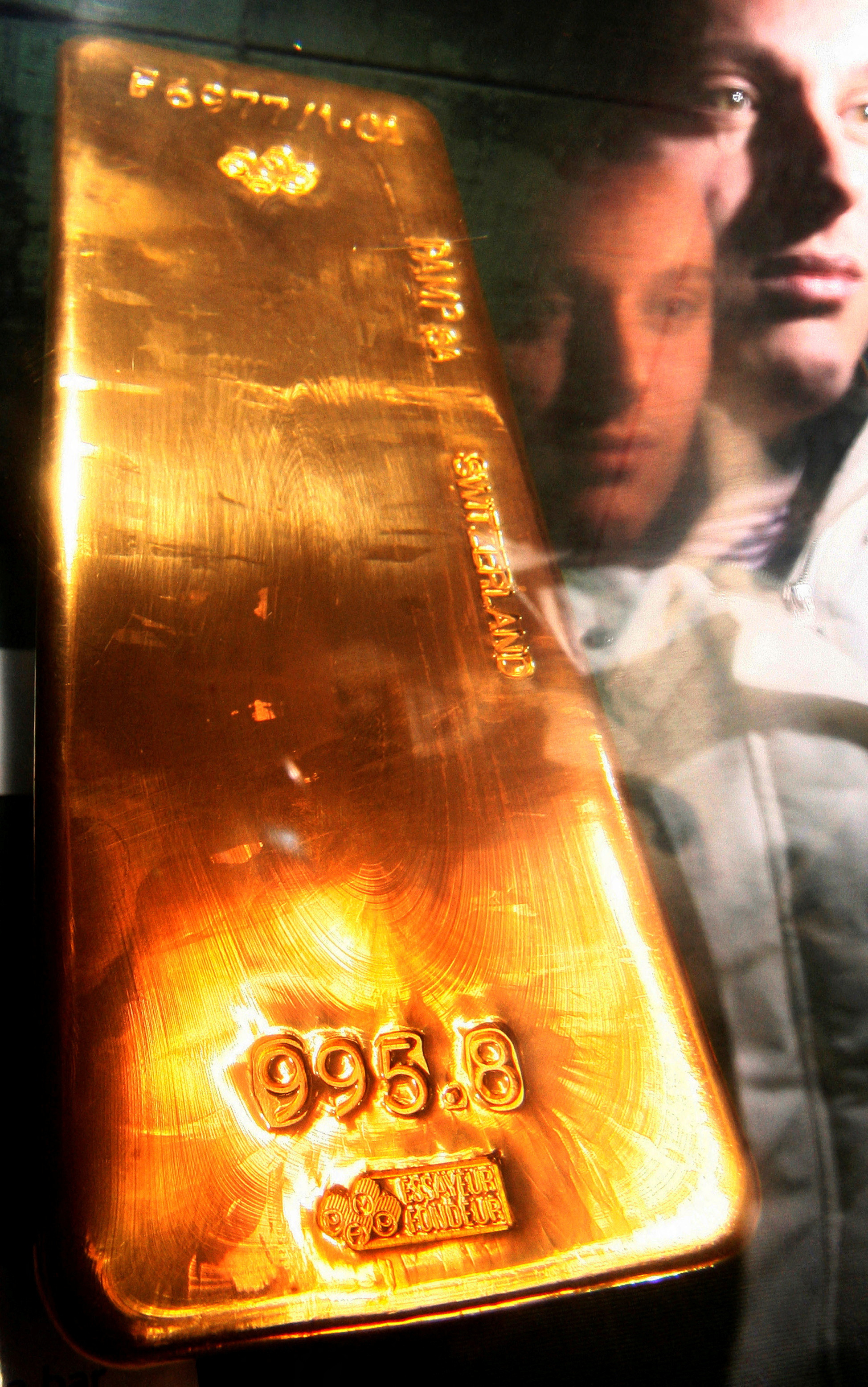 File photograph shows a tourist is reflected in perspex as he views a bar of gold bullion in the museum of the Bank of England in London