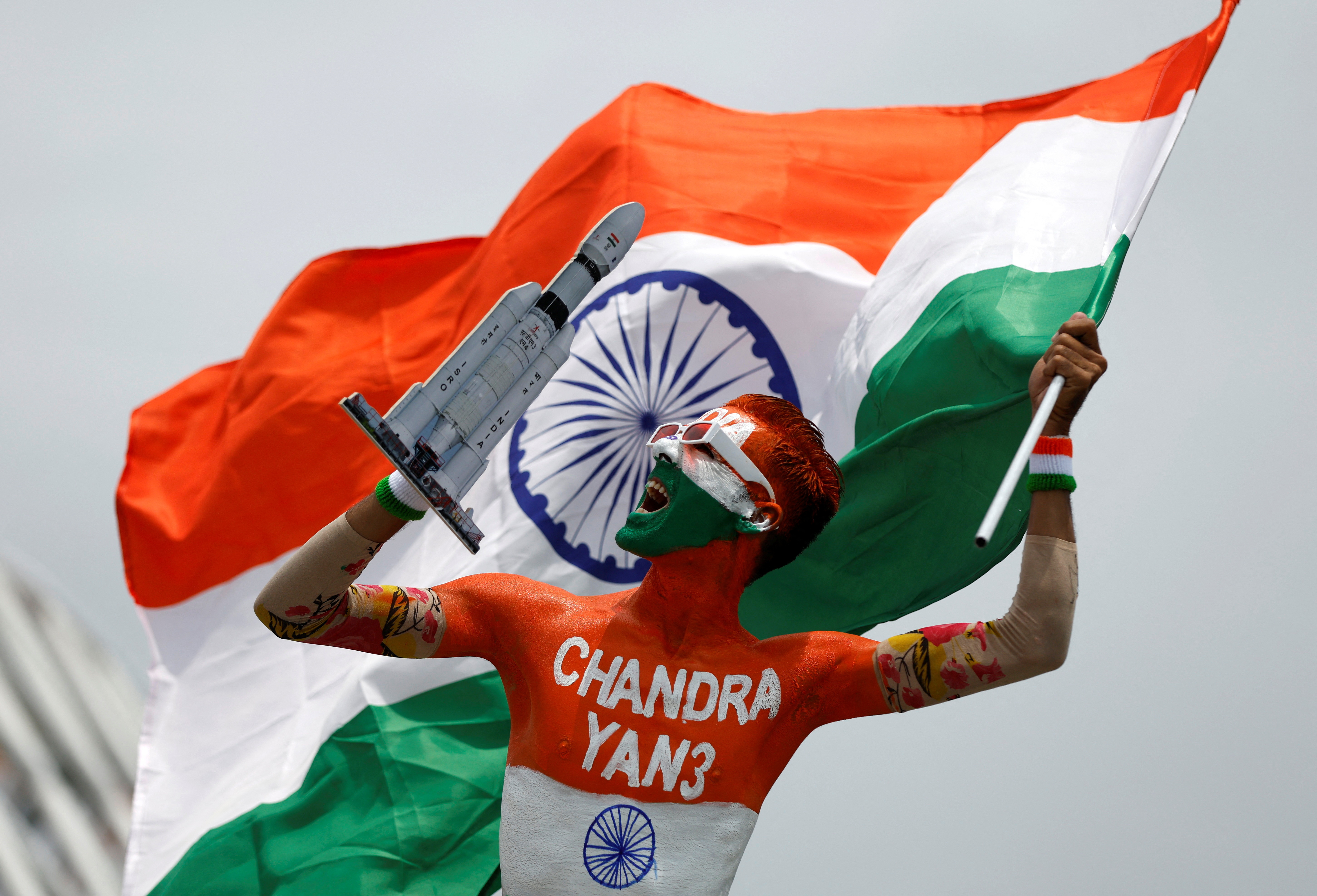 Arun Haryani, an enthusiast with his body painted in tri-colours reacts as he holds up a model of LVM3 M4 in Ahmedabad