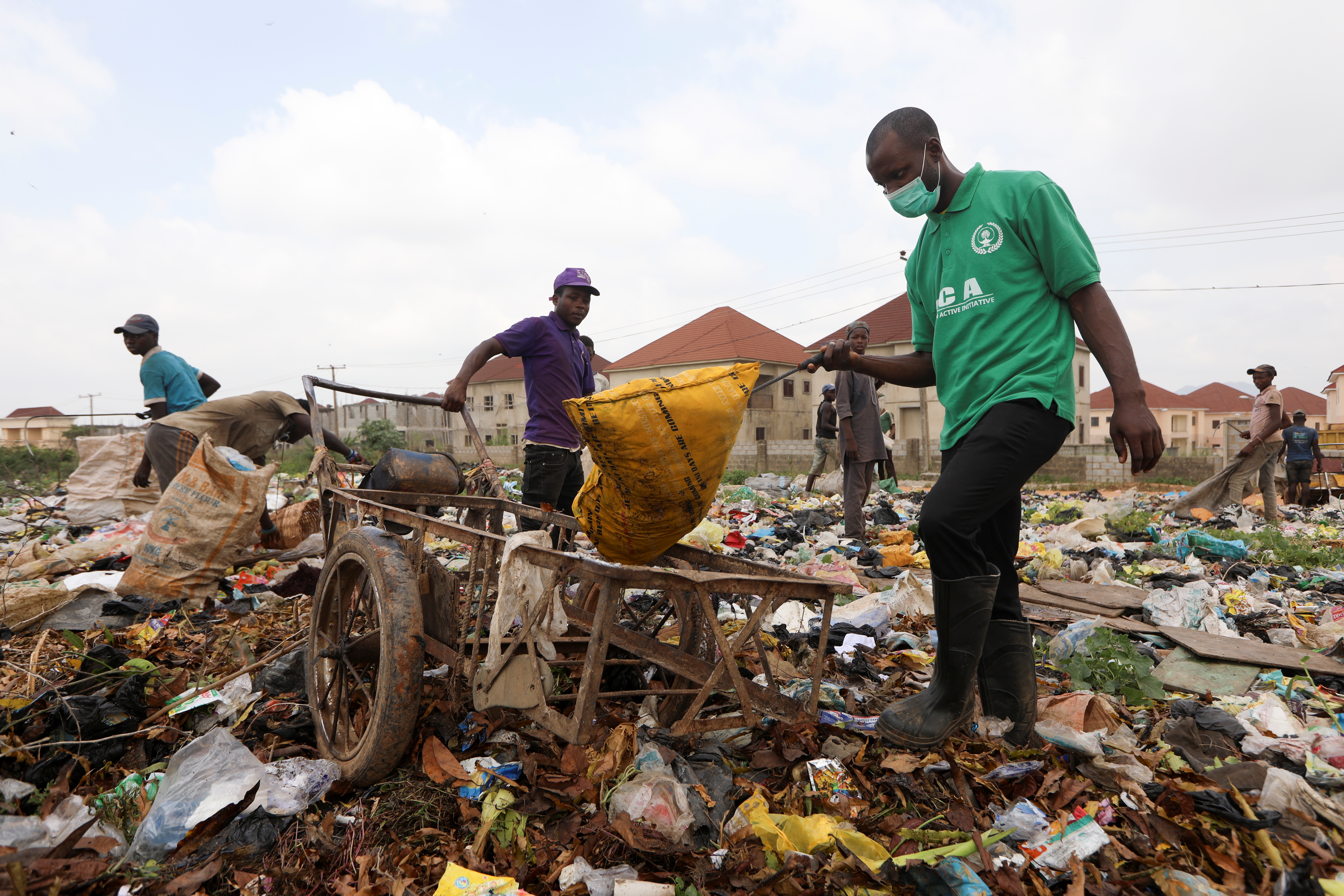 Environmental activist Goodness Dickson, of Eco Clean Active Initiative, picks up a waste item at a dumpsite in Abuja, Nigeria October 16, 2021. Picture taken October 16, 2021. REUTERS/Afolabi Sotunde