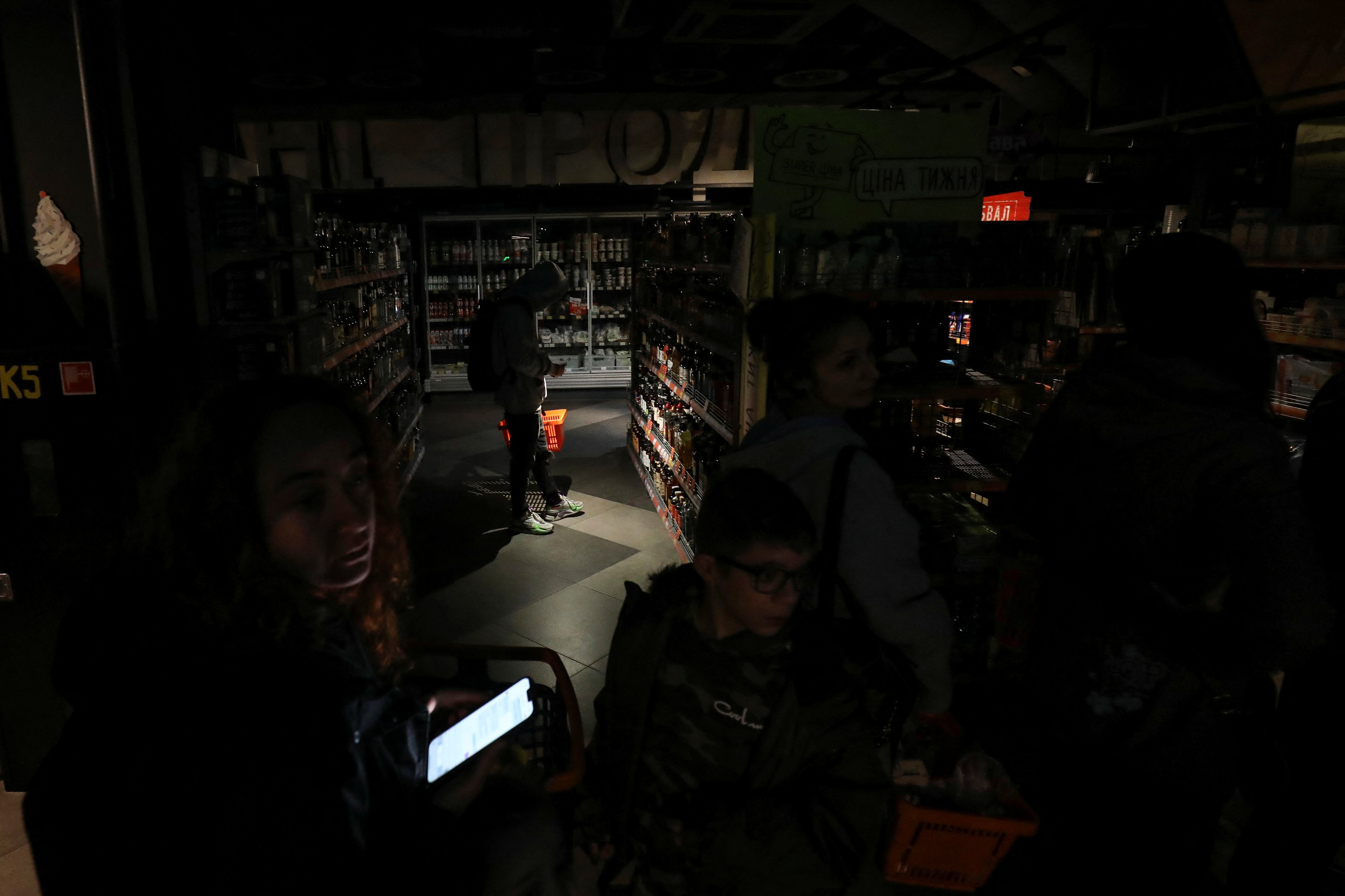 People visit a grocery store in a city centre without electricity after a Russian missile attack in Lviv