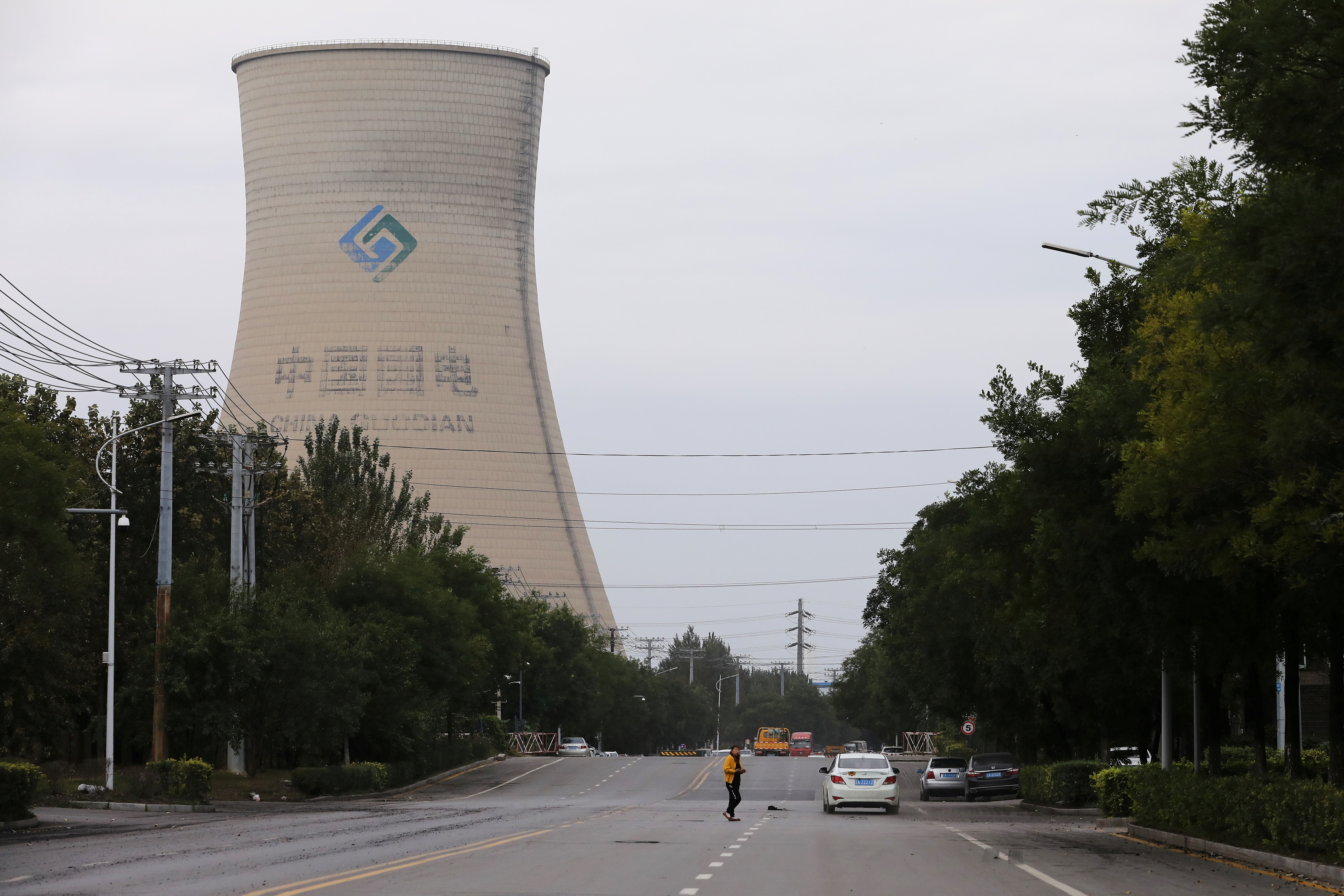 Person walks near a China Energy coal-fired power plant in Shenyang, Liaoning