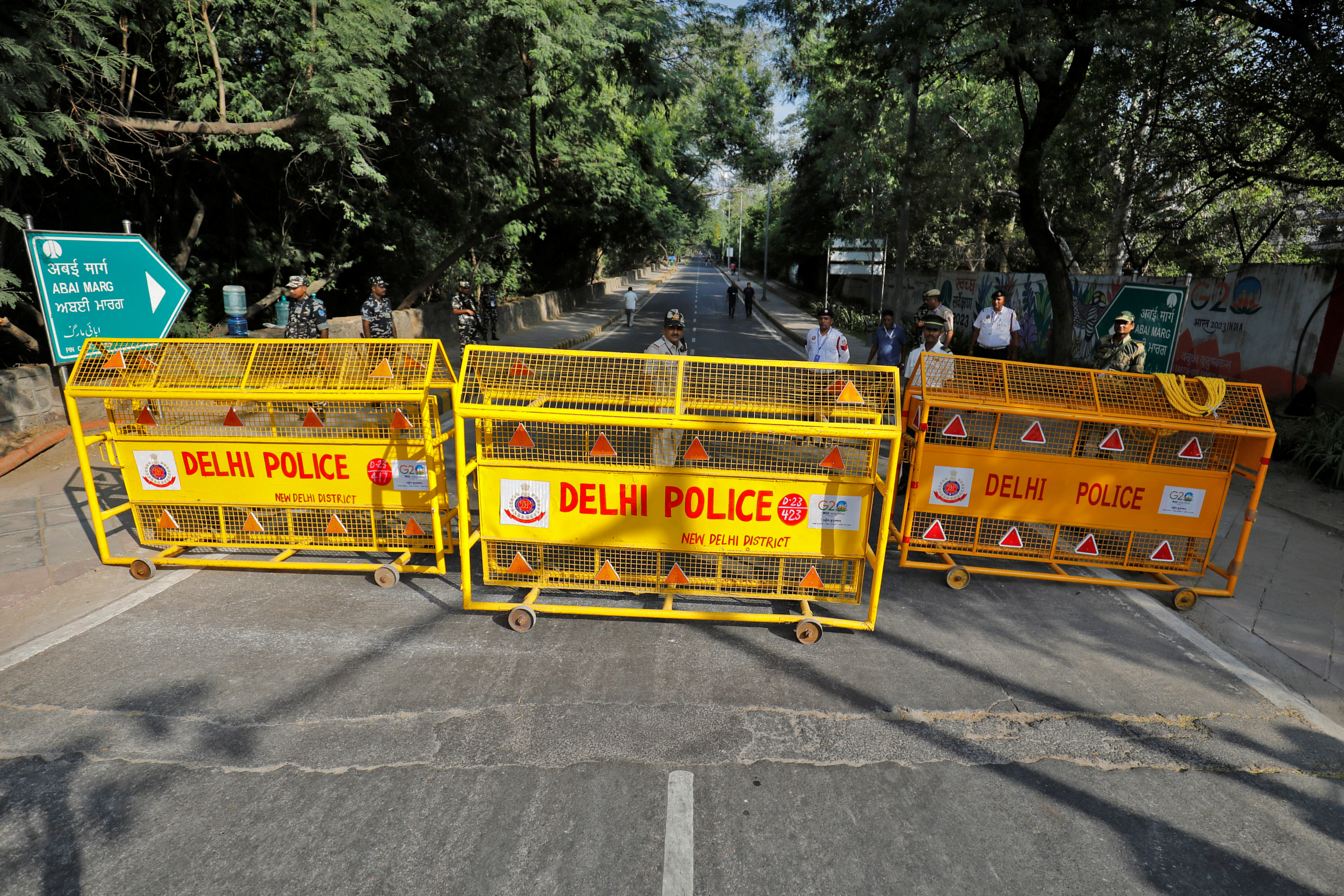 Police officers stand behind barricades on an empty road ahead of the G20 Summit in New Delhi