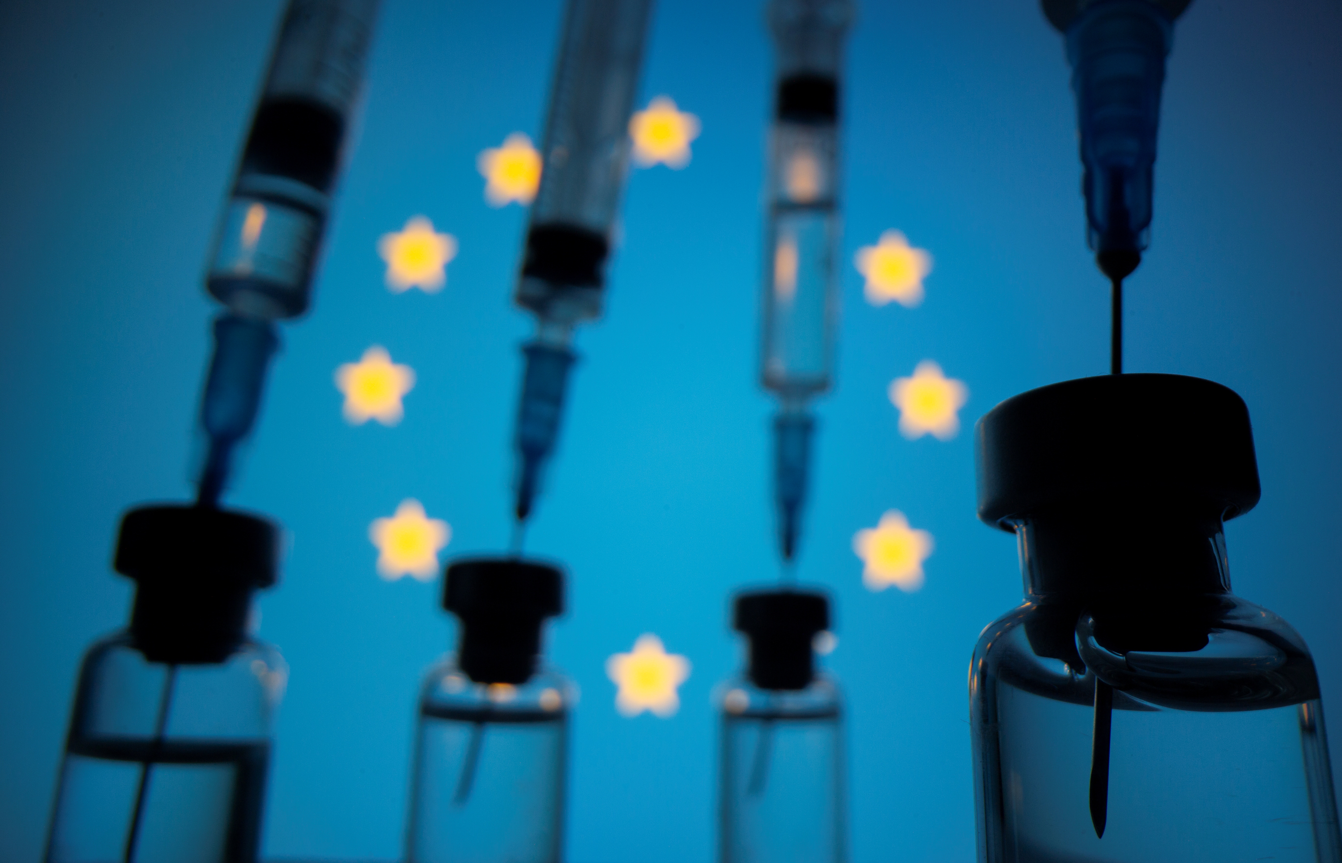 Vials and syringes are seen in front of displayed EU flag in this illustration photo
