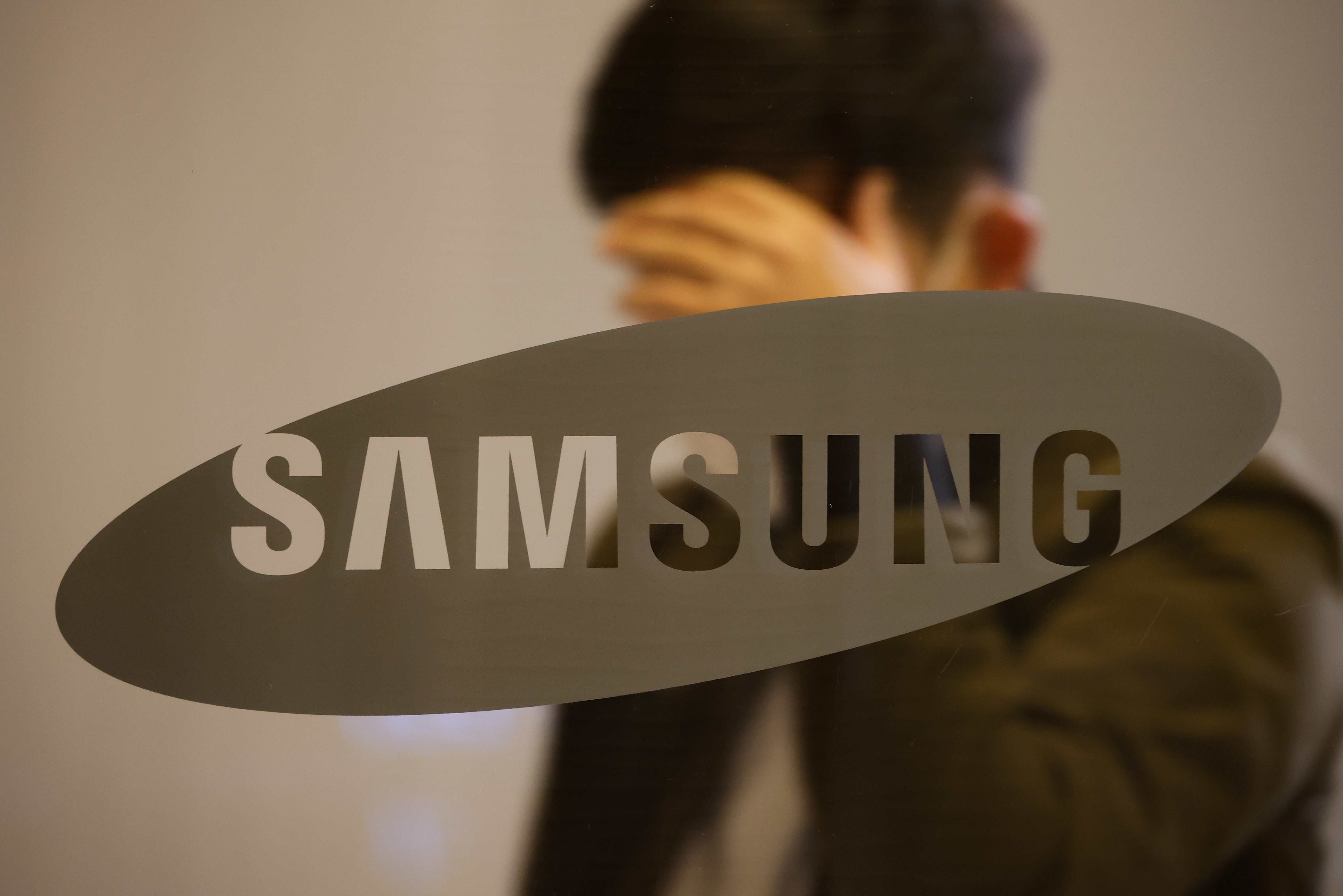 A man walks past the logo of Samsung at its office building in Seoul