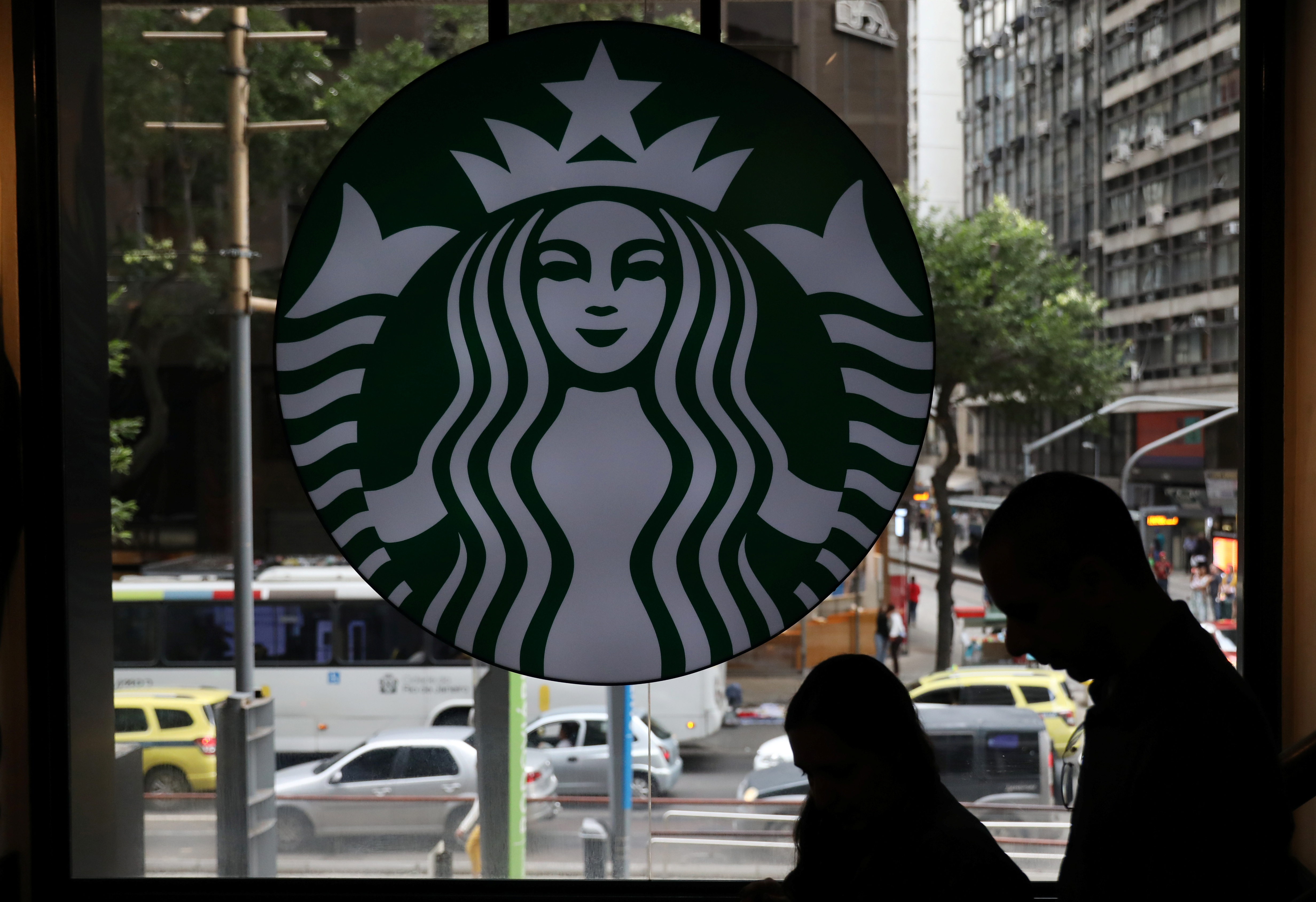 Customers pass by the logo of an American coffee company Starbucks inside a coffee shop in Rio de Janeiro