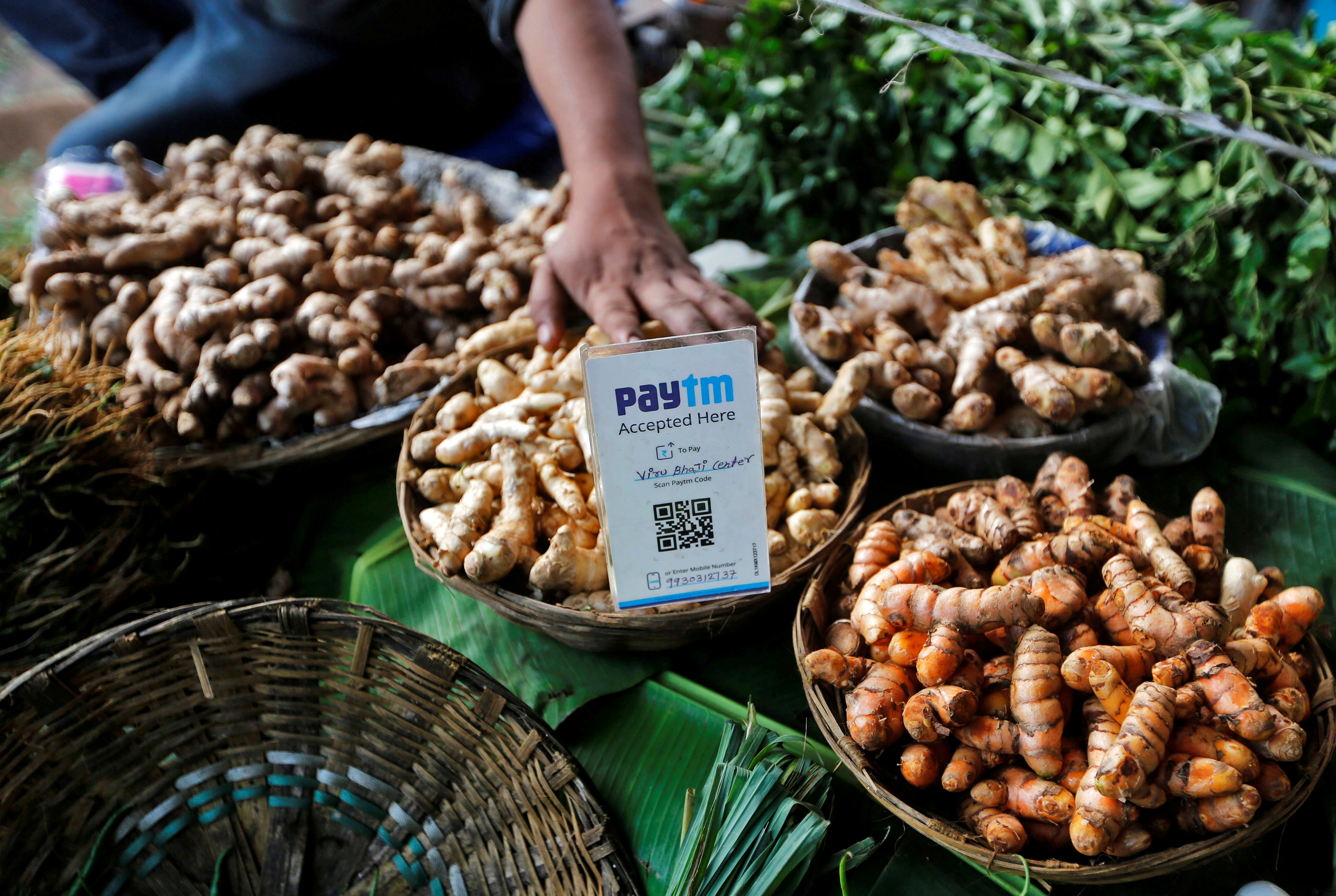 An advertisement board displaying a QR code for Paytm, a digital wallet company, is seen placed amidst vegetables at a roadside vendor's stall in Mumbai