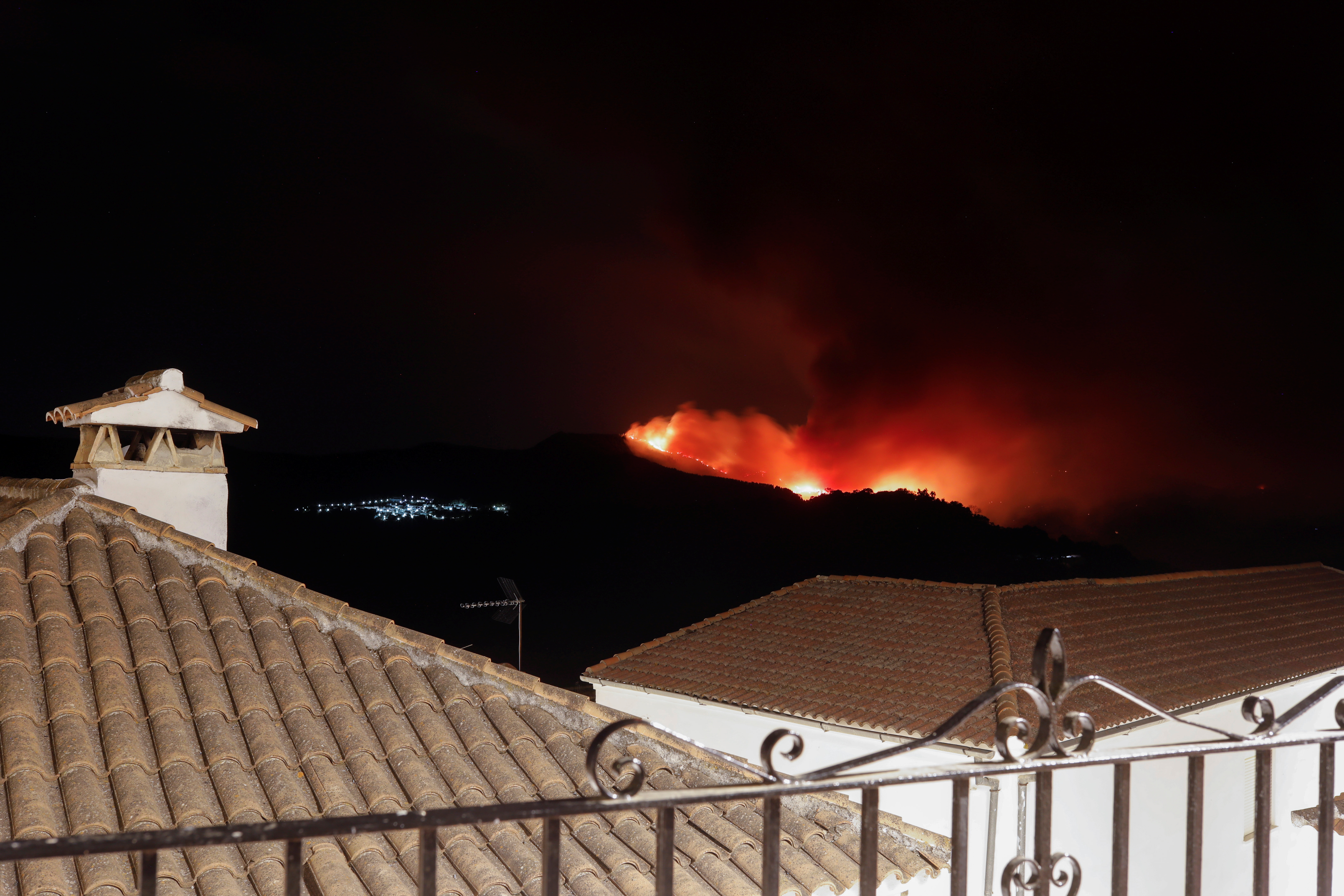 A wildfire is seen from a balcony near the town of Pujerra, which was evacuated, in Cartajima, near Estepona, Spain, September 12, 2021. REUTERS/Jon Nazca