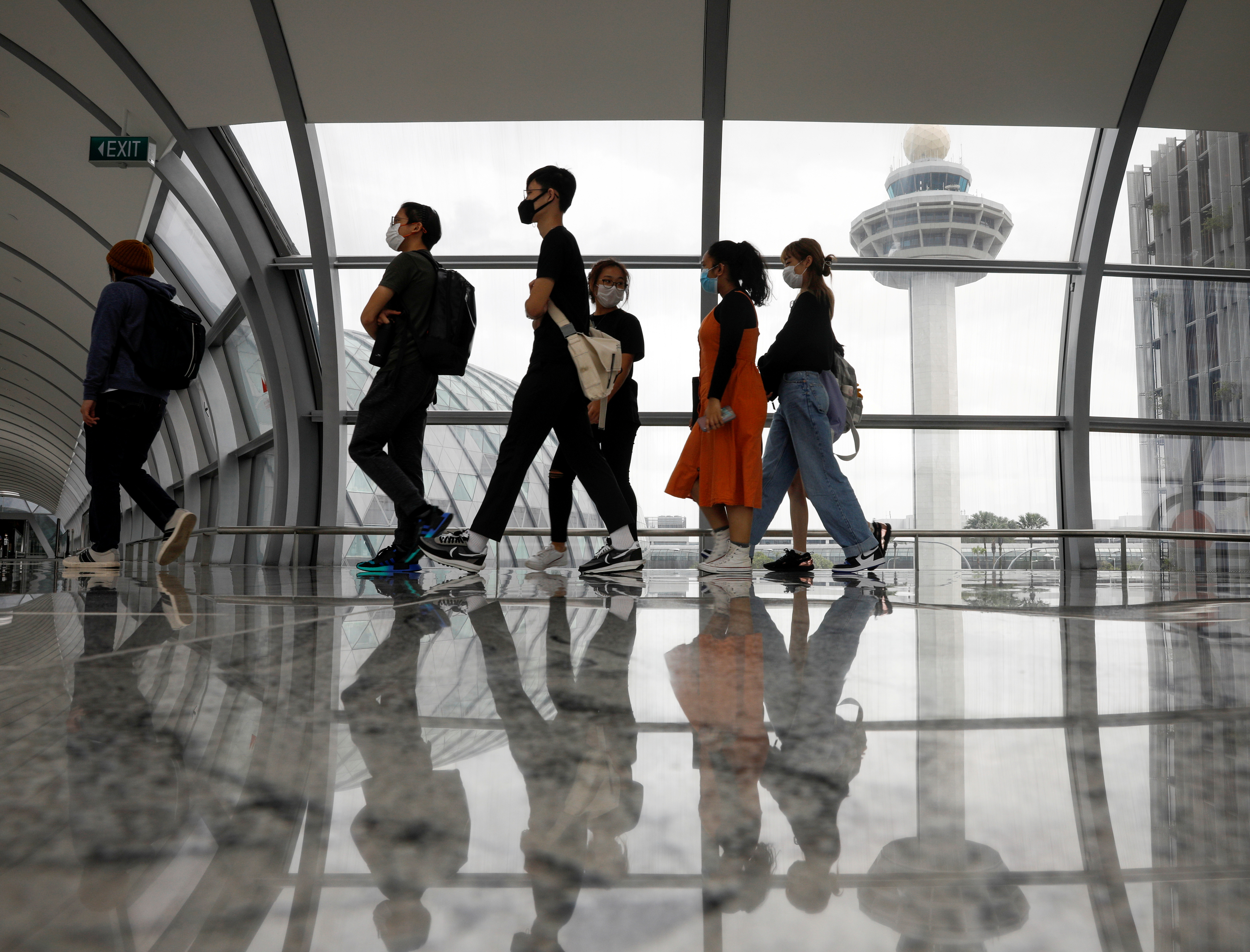 People pass the control tower of Singapore's Changi Airport, Singapore January 18, 2021. REUTERS/Edgar Su/File Photo