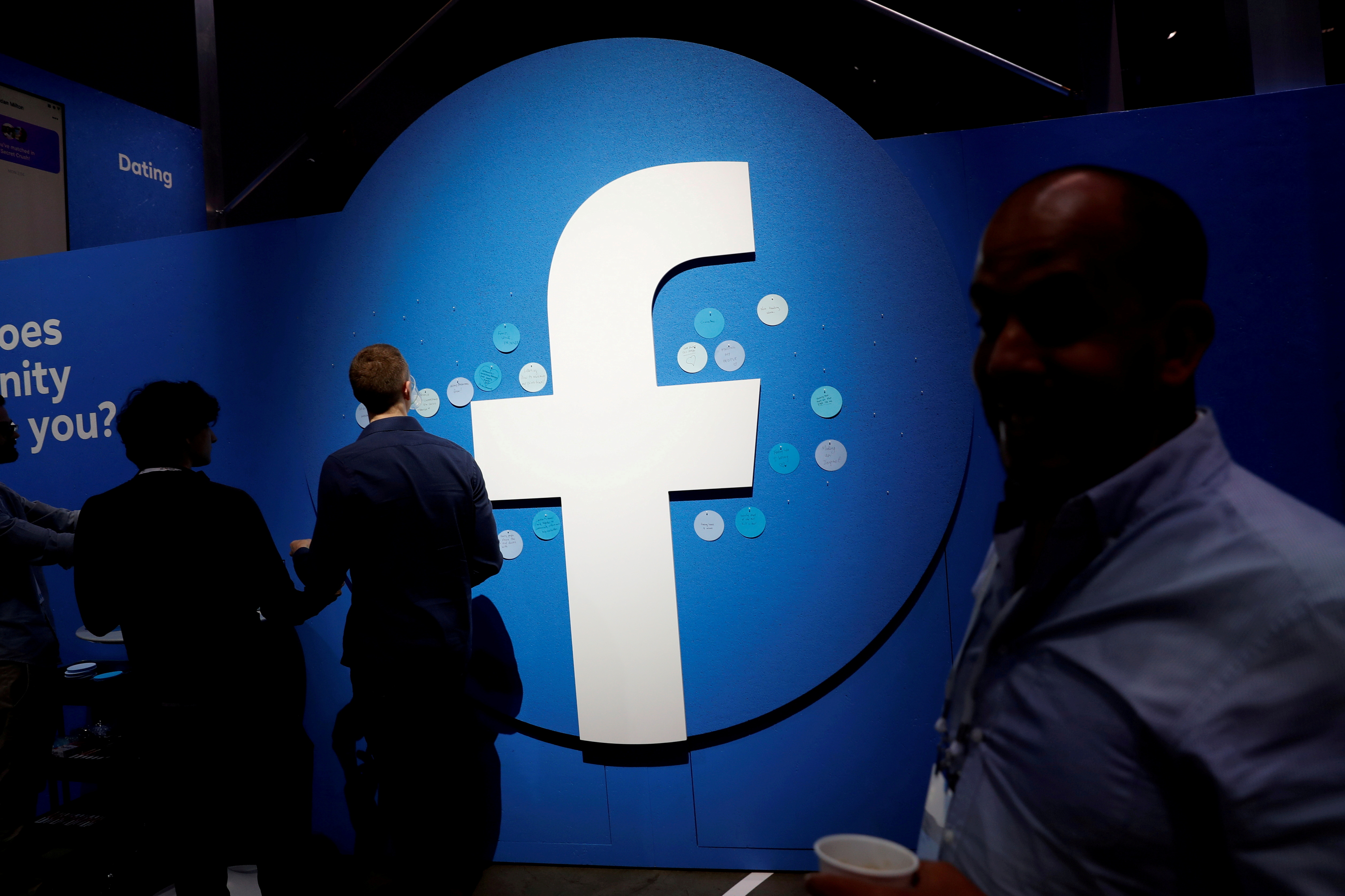 Attendees walk past a Facebook logo during Facebook Inc's F8 developers conference in San Jose