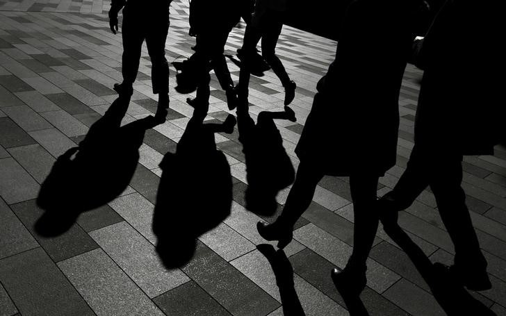 Workers cast shadows as they stroll among the office towers Sydney's Barangaroo business district in Australia's largest city
