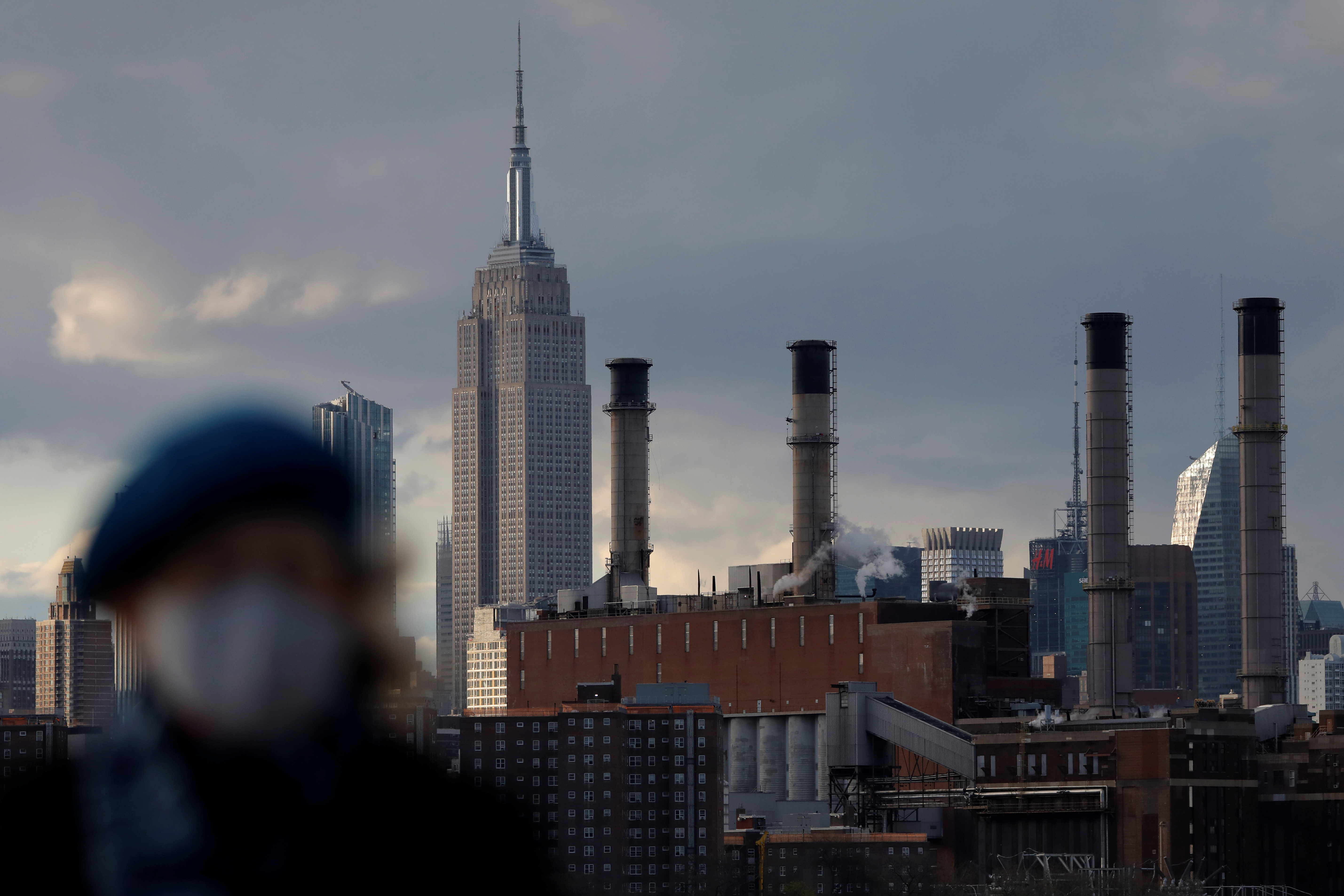 A person walks in front of the Con Edison power generating plant in Manhattan, New York City, New York