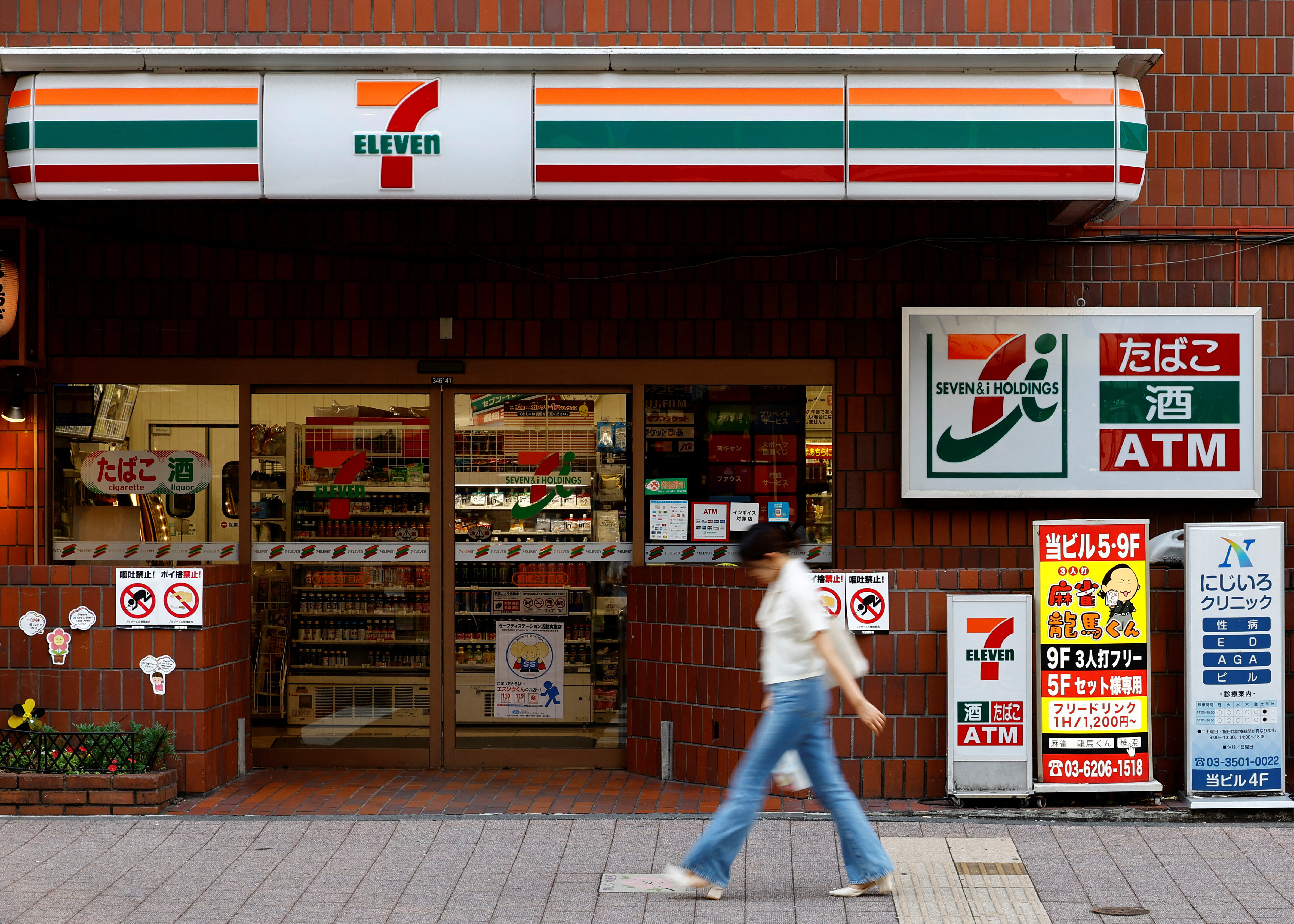 A pedestrian walks past Japan's Seven & I’s 7-Eleven convenience store in Tokyo