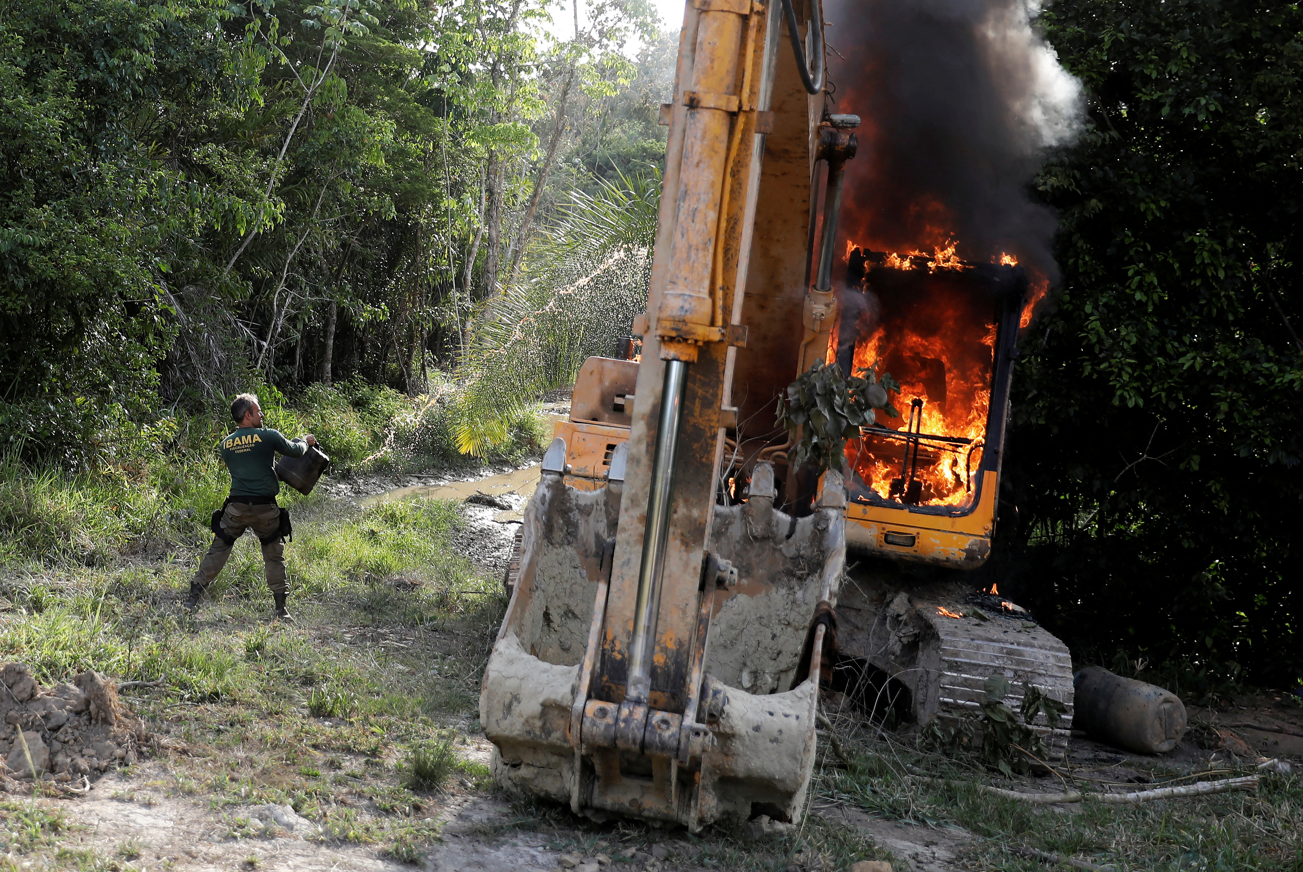 An agent of the Brazilian Institute for the Environment and Renewable Natural Resources (IBAMA) throws oil at a machine to destroy it at an illegal gold mine during an operation conducted jointly with the Federal Police near the city of Altamir