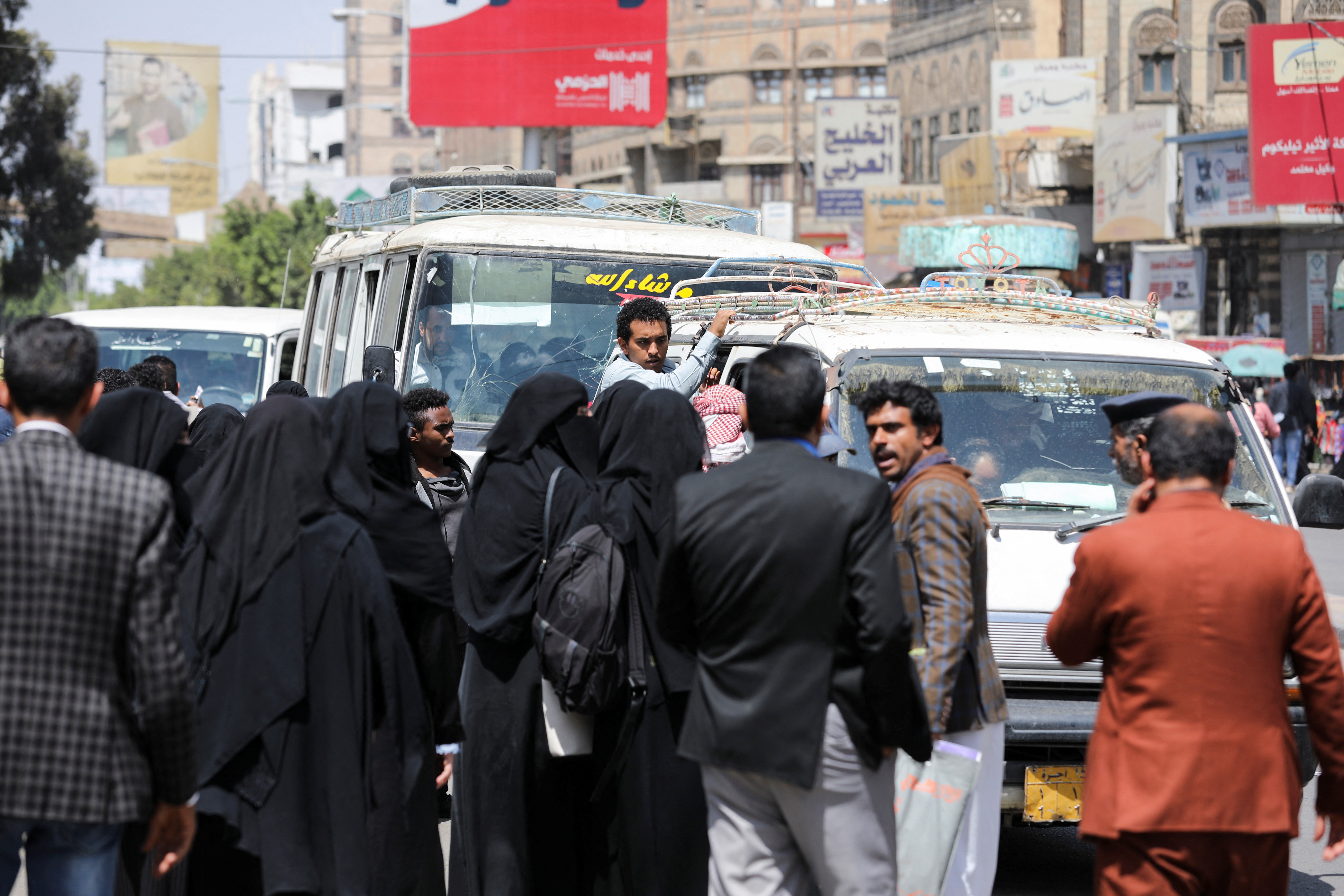 People wait for buses on a street amid an acute fuel shortage in Sanaa