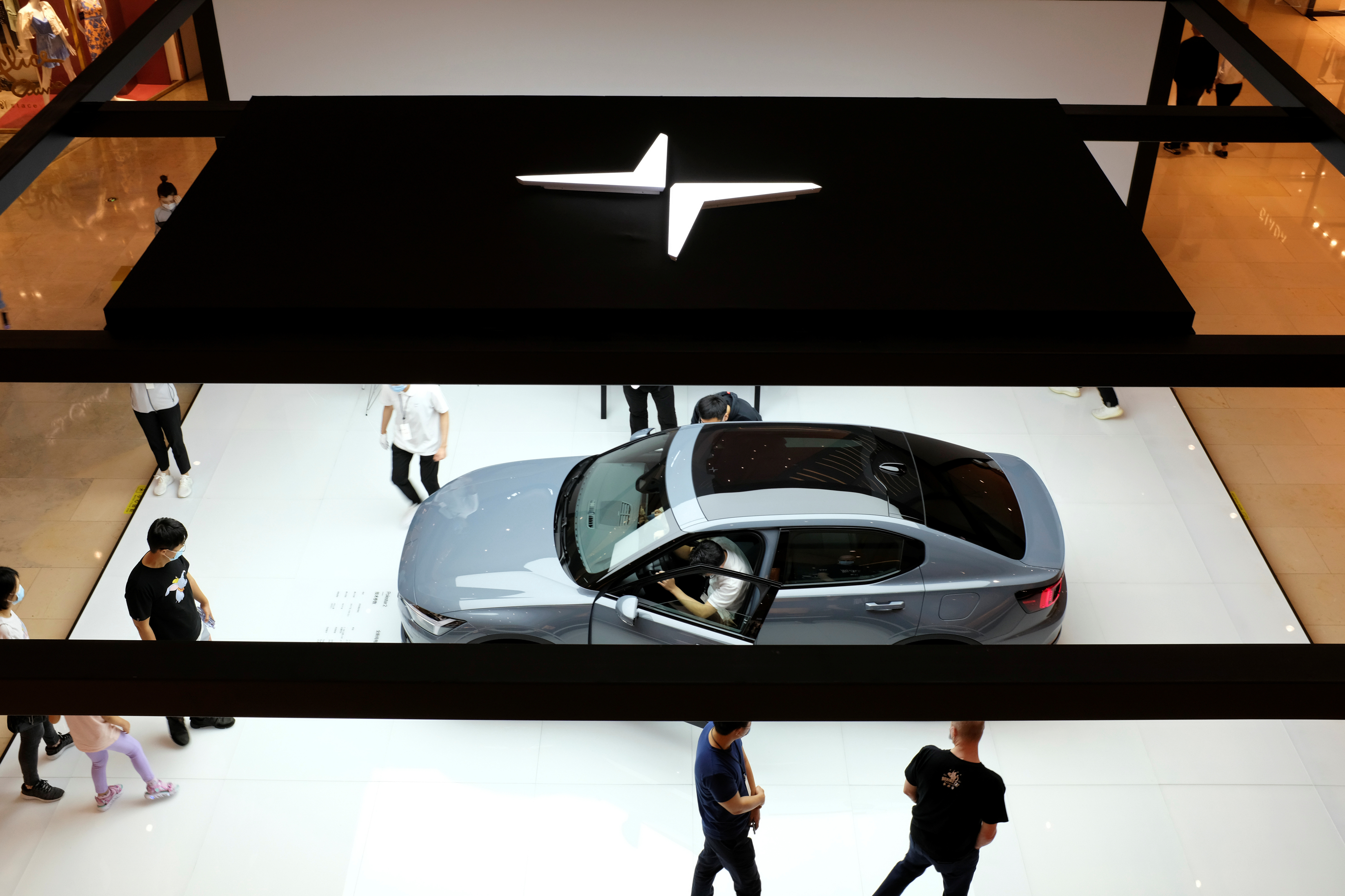 People look at a Polestar 2 electric sedan displayed in a shopping mall in Shanghai