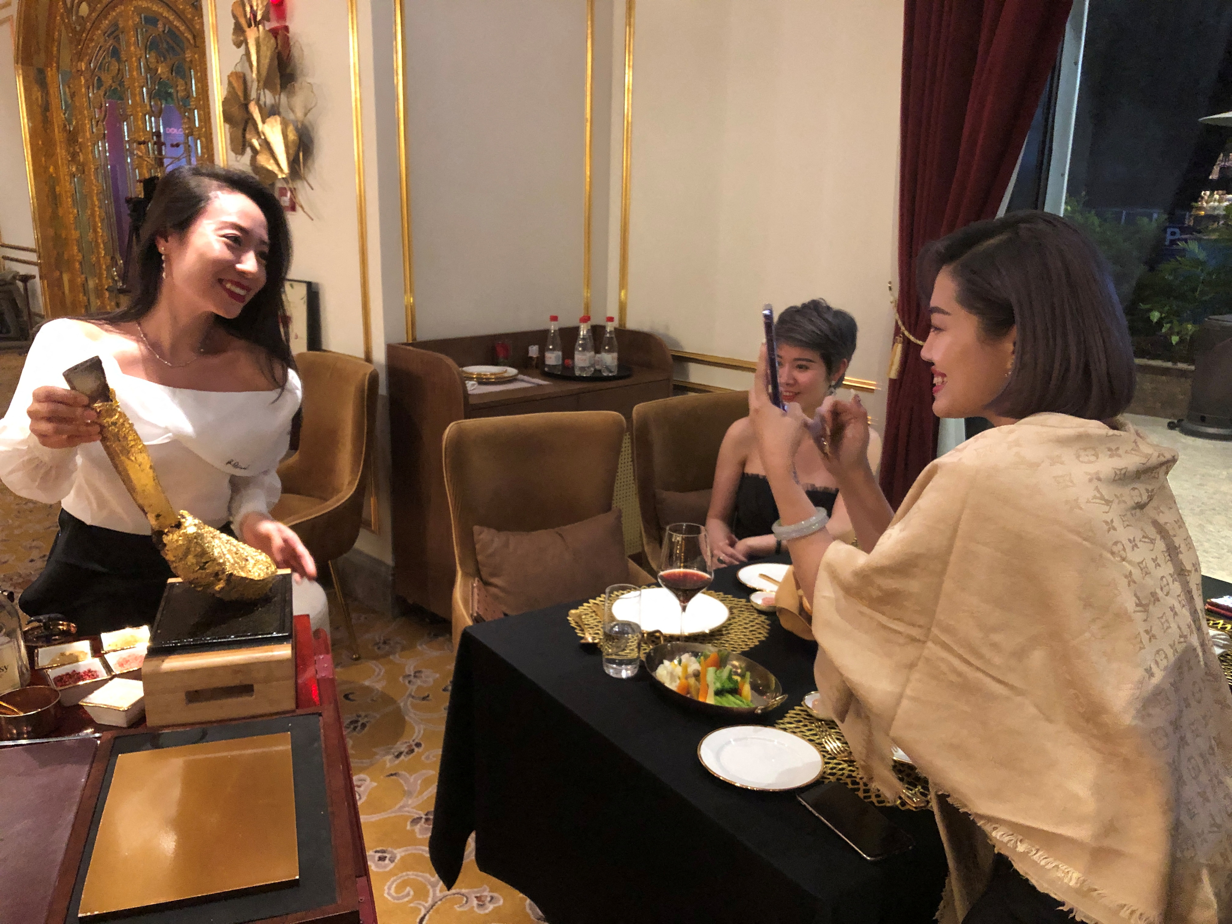 Customers take pictures with a gold leaf-coated steak, at a Dolce By Wyndham Hanoi Golden Lake hotel, in Hanoi