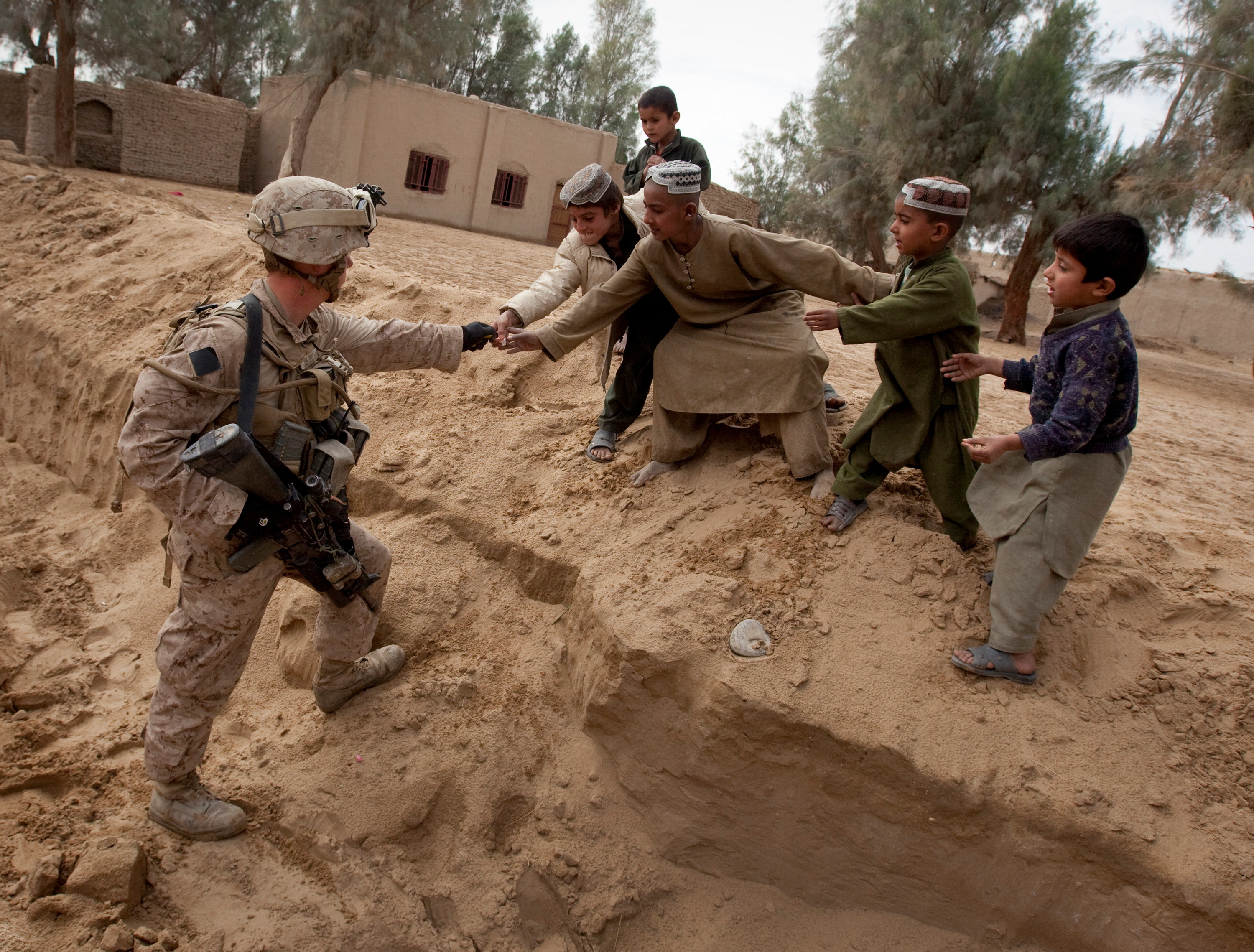 U.S. Marine Selby hands candy to local Afghan boys while keeping guard over a meeting of leaders in the Garmsir district of Helmand Province